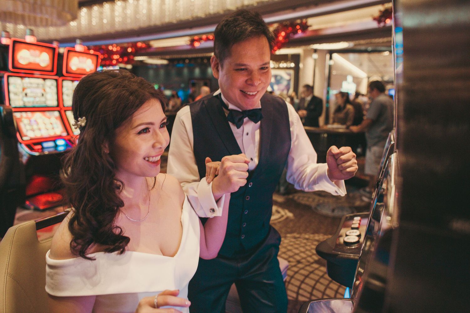 Excited couple celebrating a slot machine win at a casino, dressed in elegant formal attire.