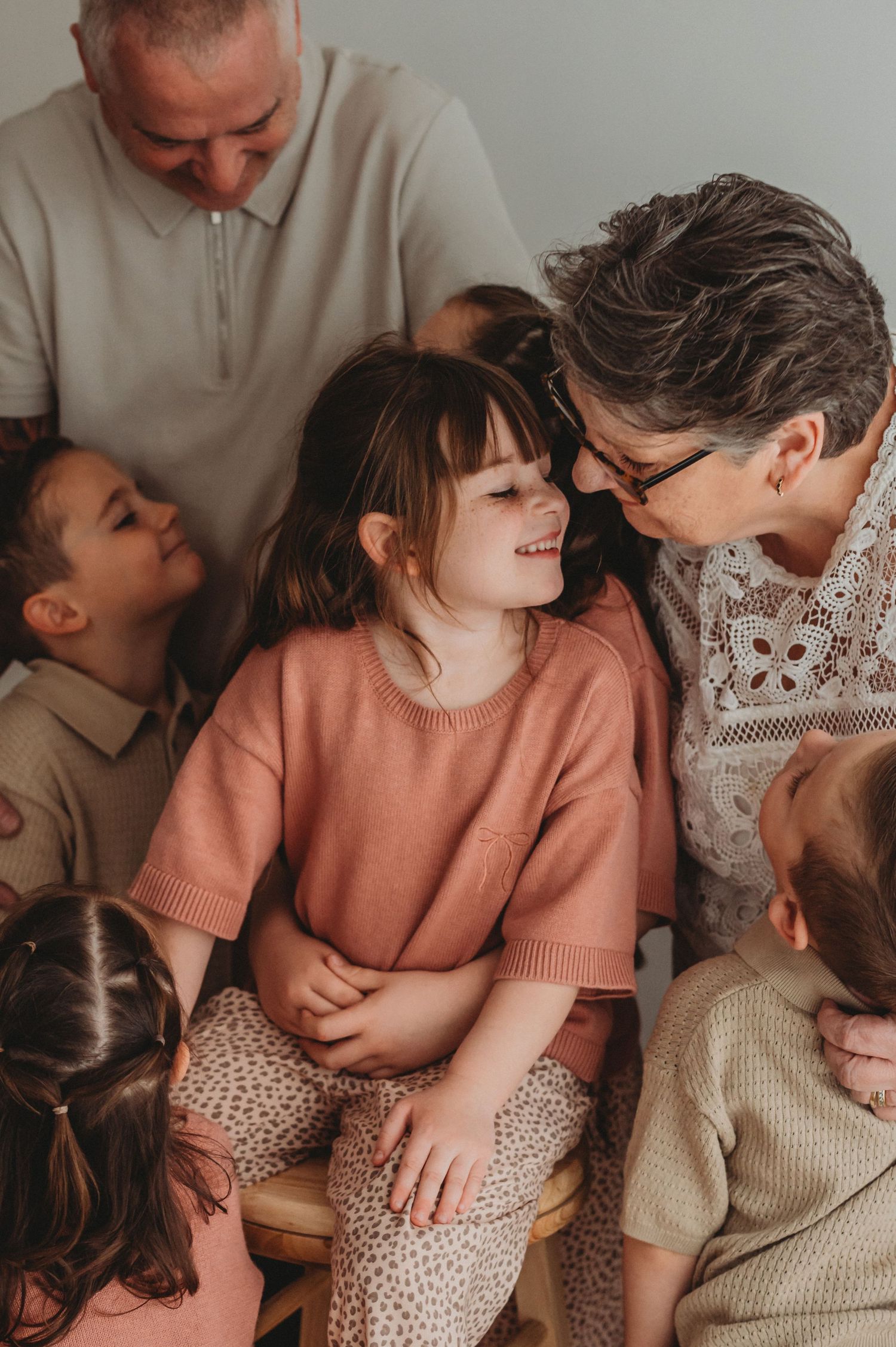 Grandparents surrounded by grandchildren sharing a warm moment indoors.
