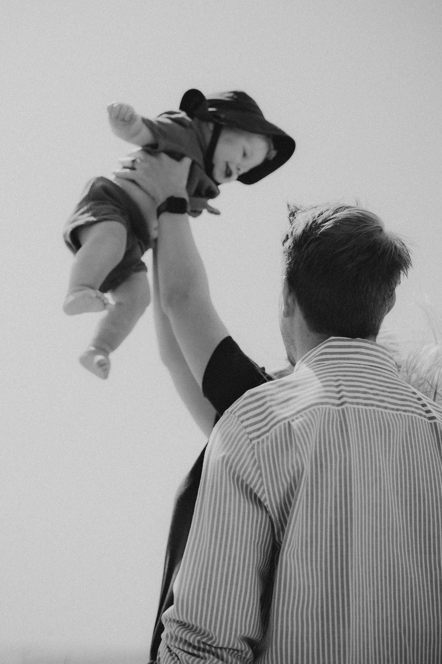 Black and white photo of father lifting baby in the air.