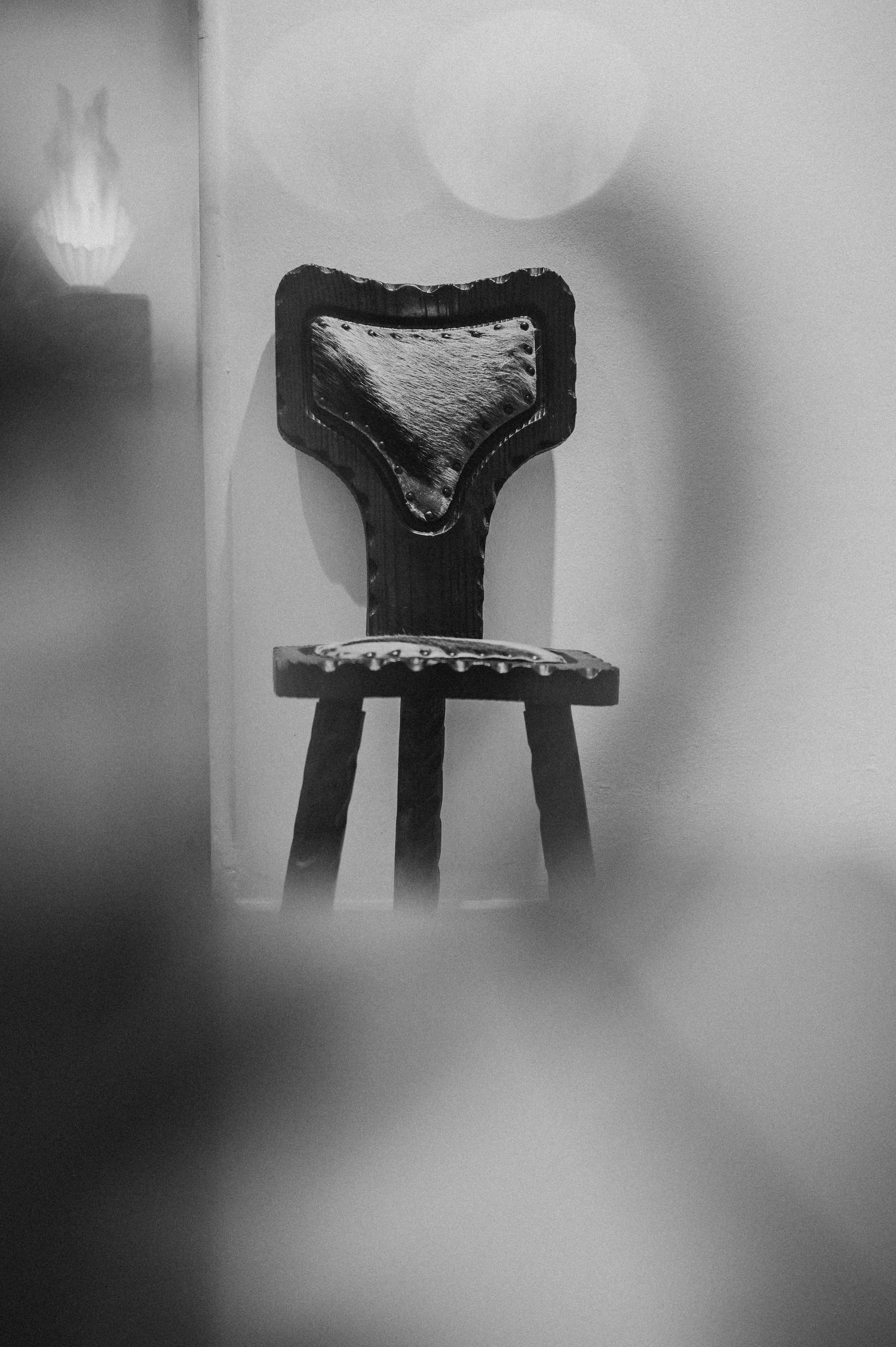 Vintage ornate wooden chair with upholstered back photographed in moody black and white light.