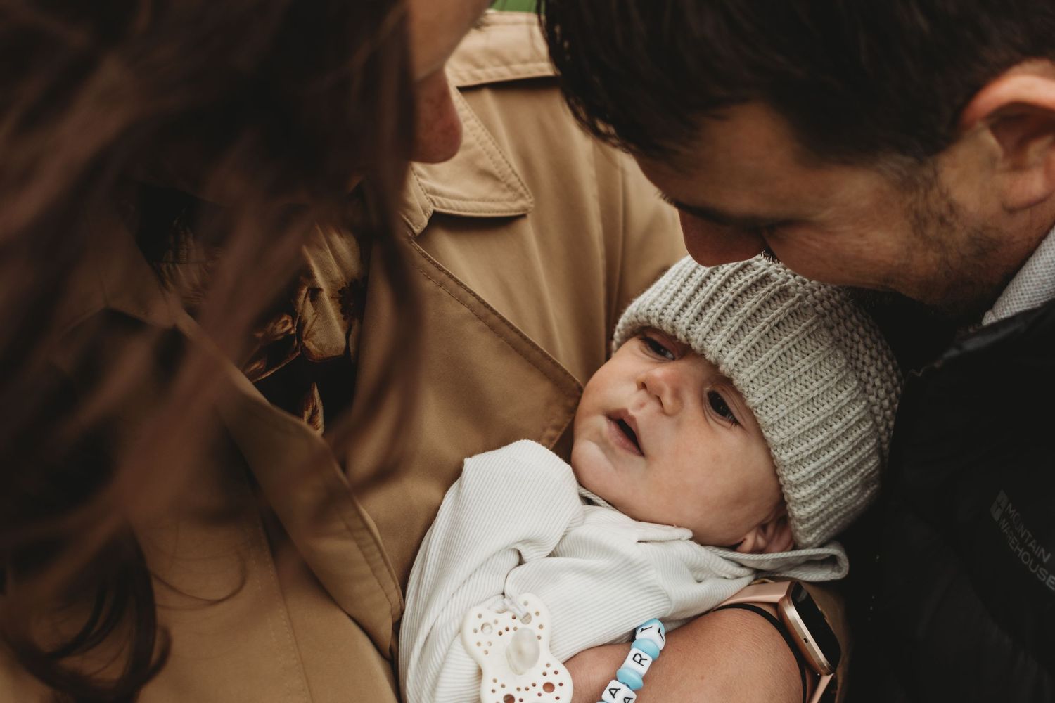 Loving parents tenderly holding their newborn baby in soft warm light.