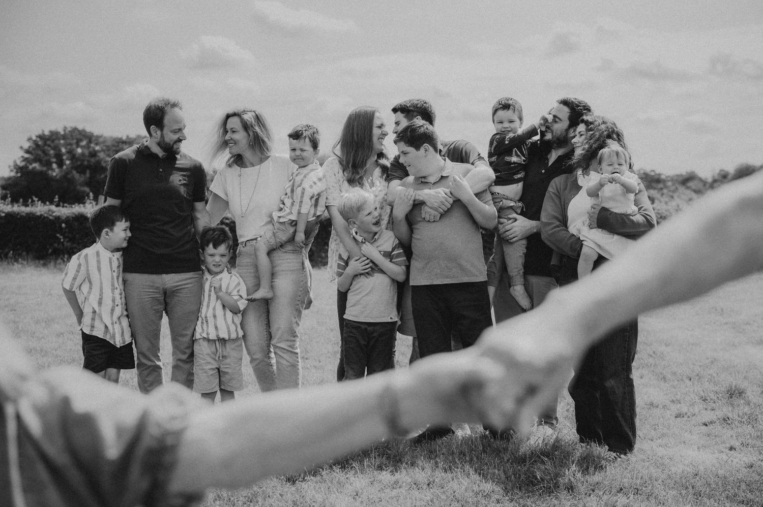 Black and white photo of a large multigenerational family gathering together in an open field.