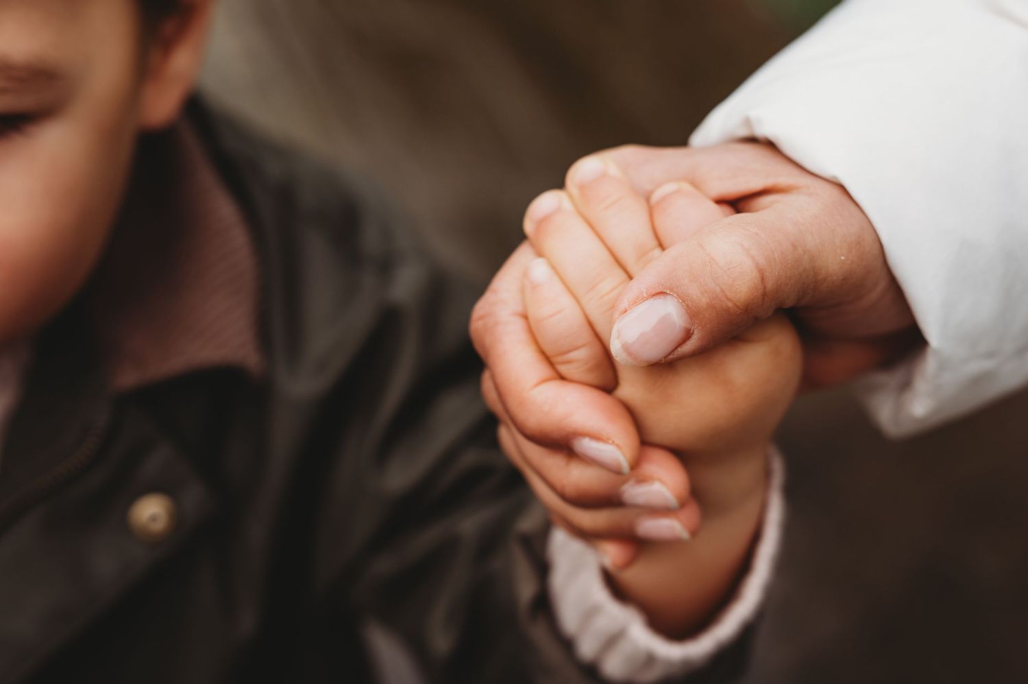 Close-up of an adult and child holding hands tenderly, showcasing a gentle family bond.