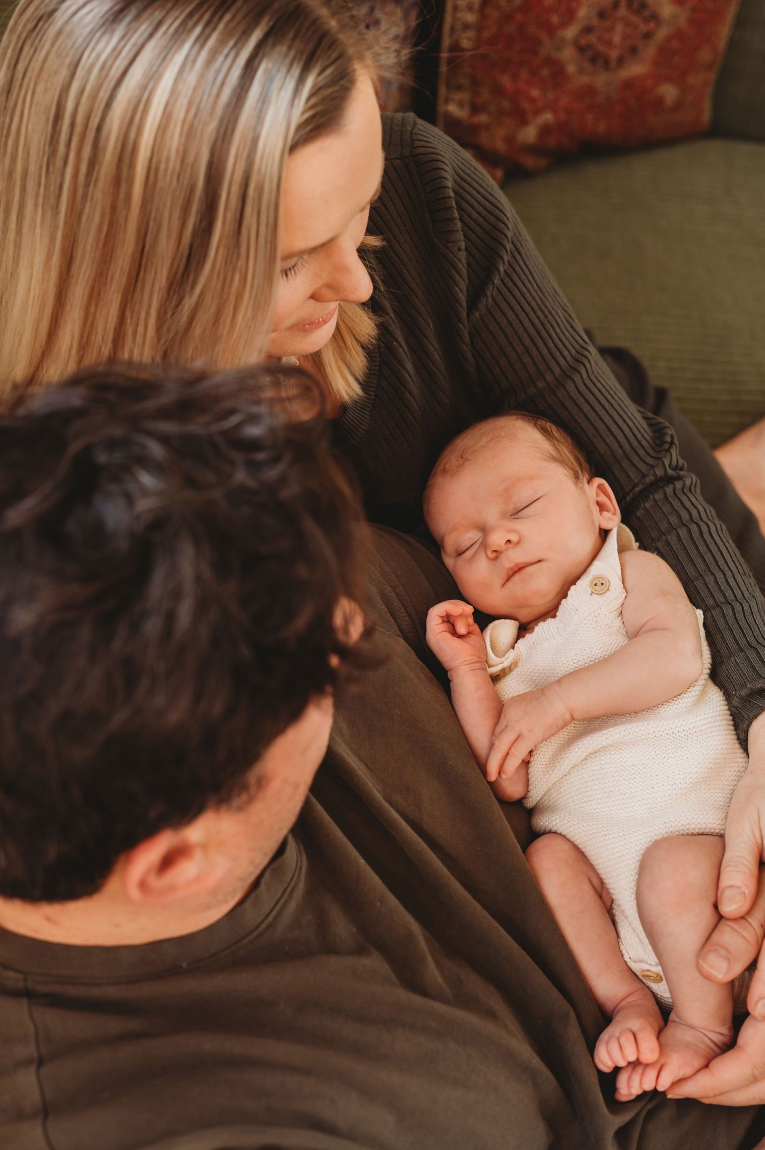 New parents lovingly gaze at their peaceful sleeping newborn baby in a warm home setting.