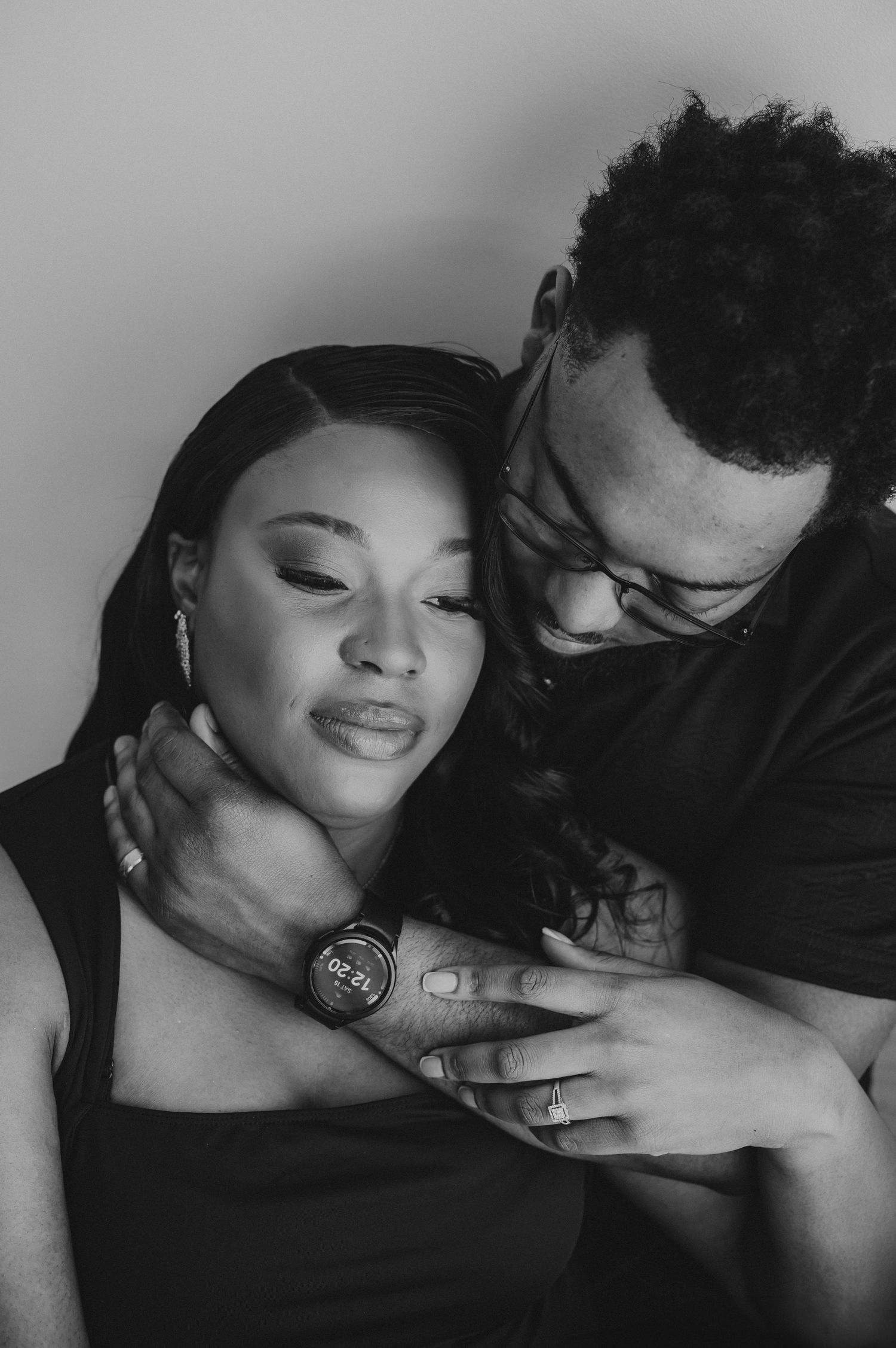 Black and white intimate portrait of a couple embracing tenderly in a studio setting.