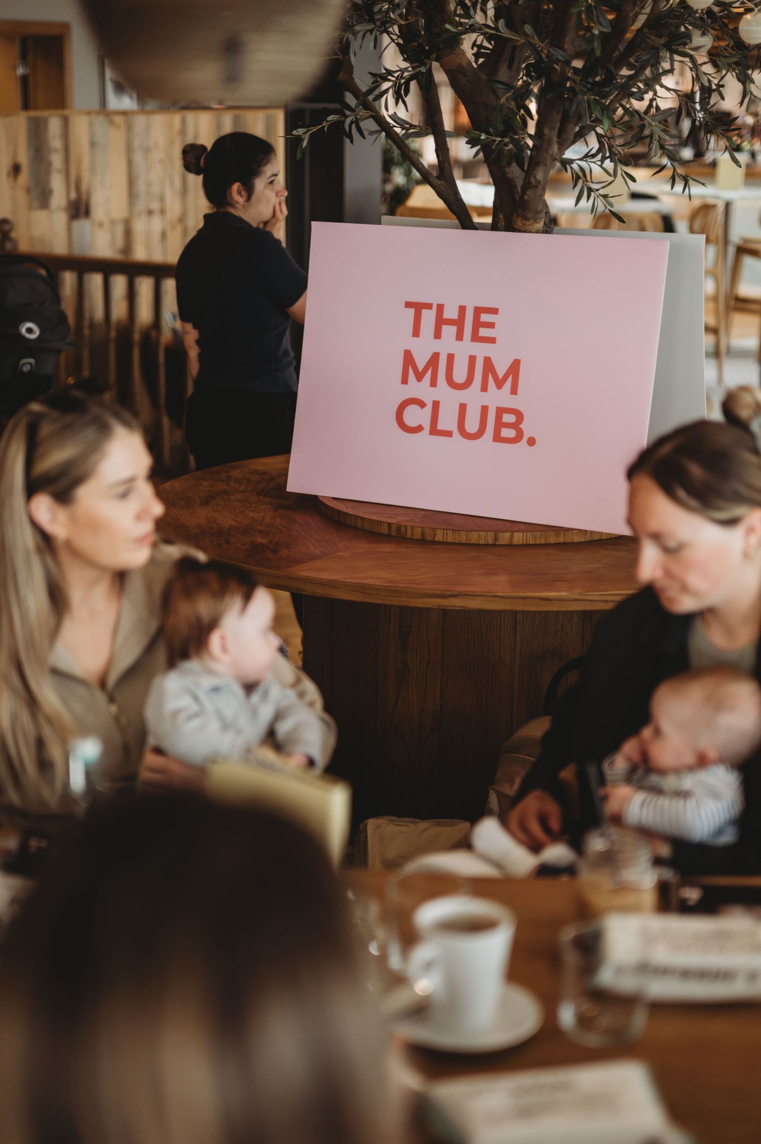 The Mum Club sign displayed prominently at a mothers and babies cafe social event.