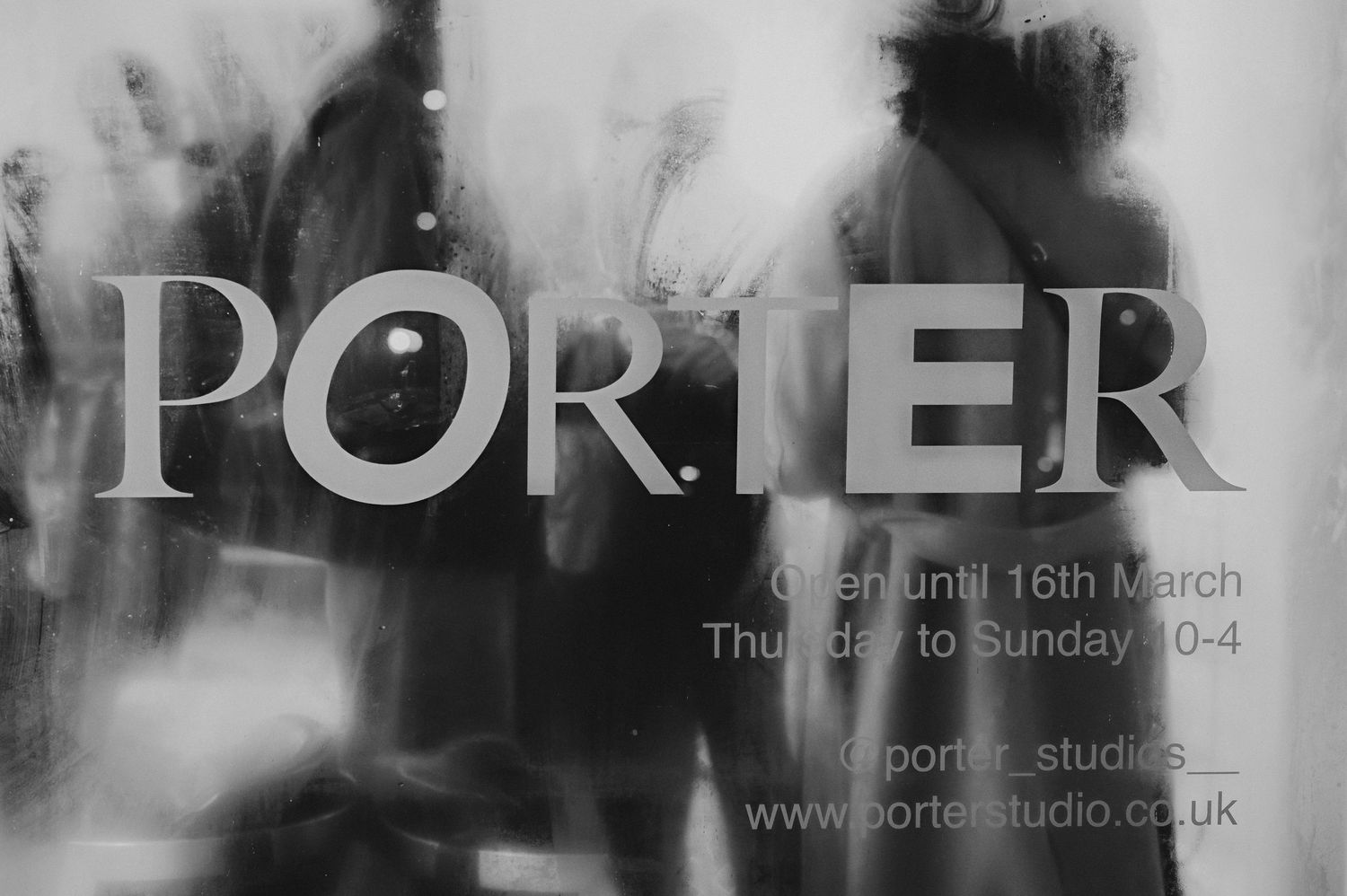Black and white photo of people walking past Porter Studio storefront window.