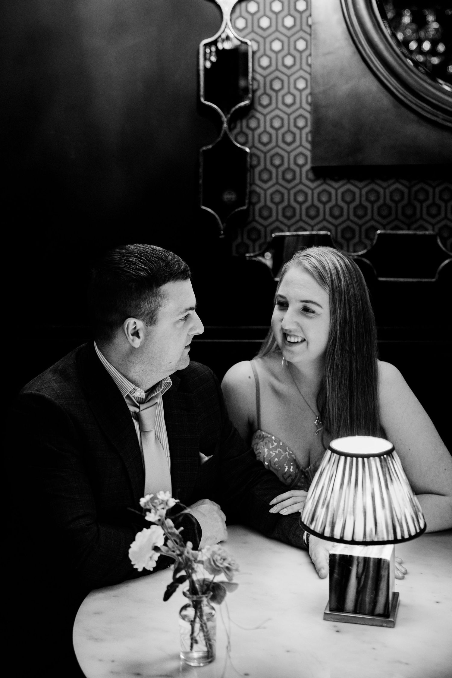 Black and white image of a smiling couple enjoying a conversation at a dimly lit restaurant.