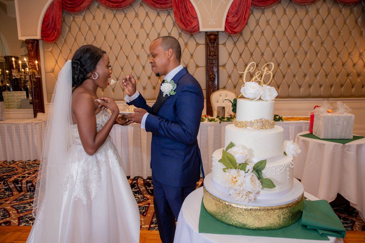 Bride and groom smiling while cutting cake during reception