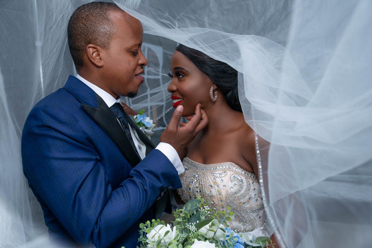 Bride and groom wrapped in veil sharing romantic moment