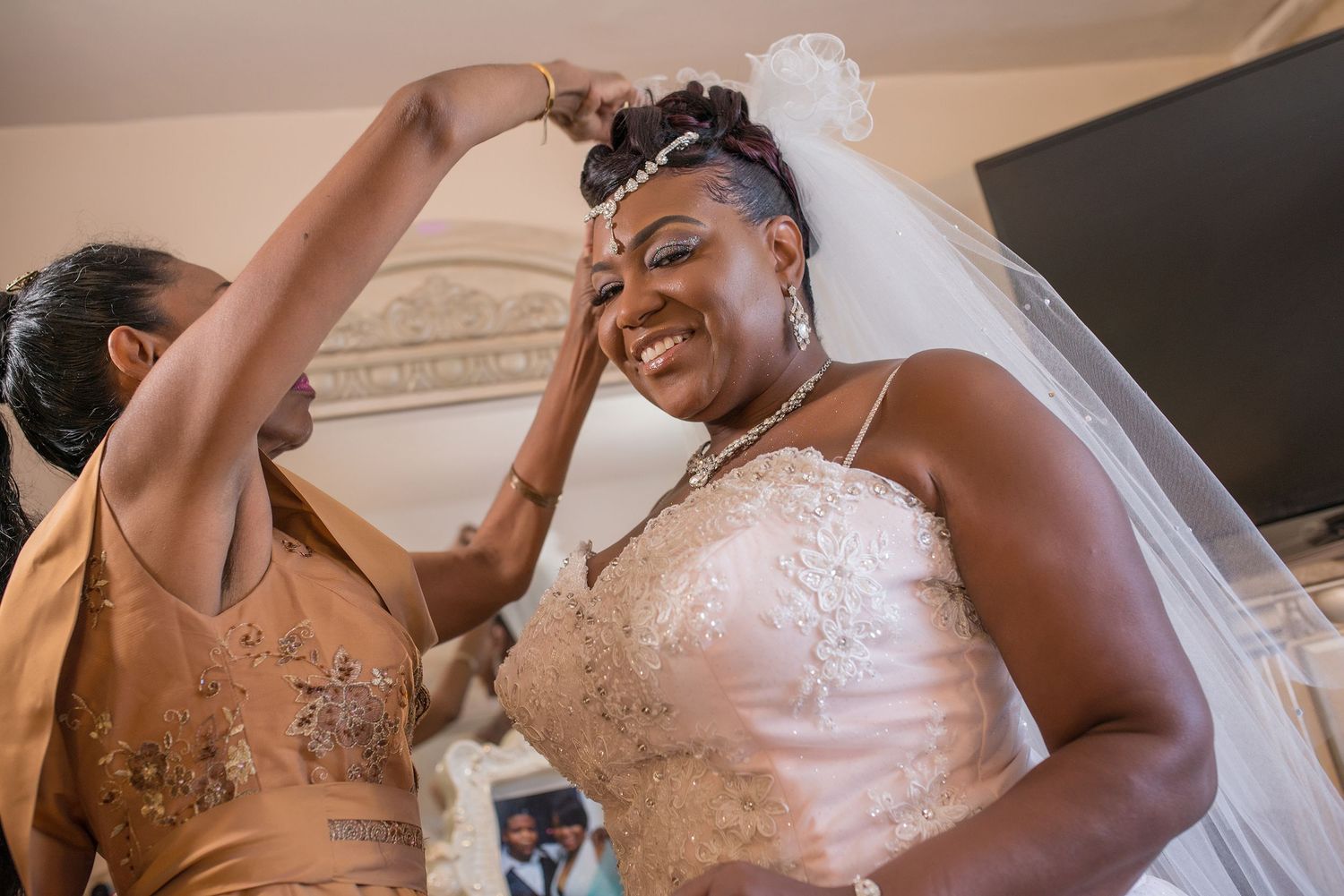 Bride getting ready while a loved one helps place jewelry before the wedding ceremony.by Magic All Moment Photography