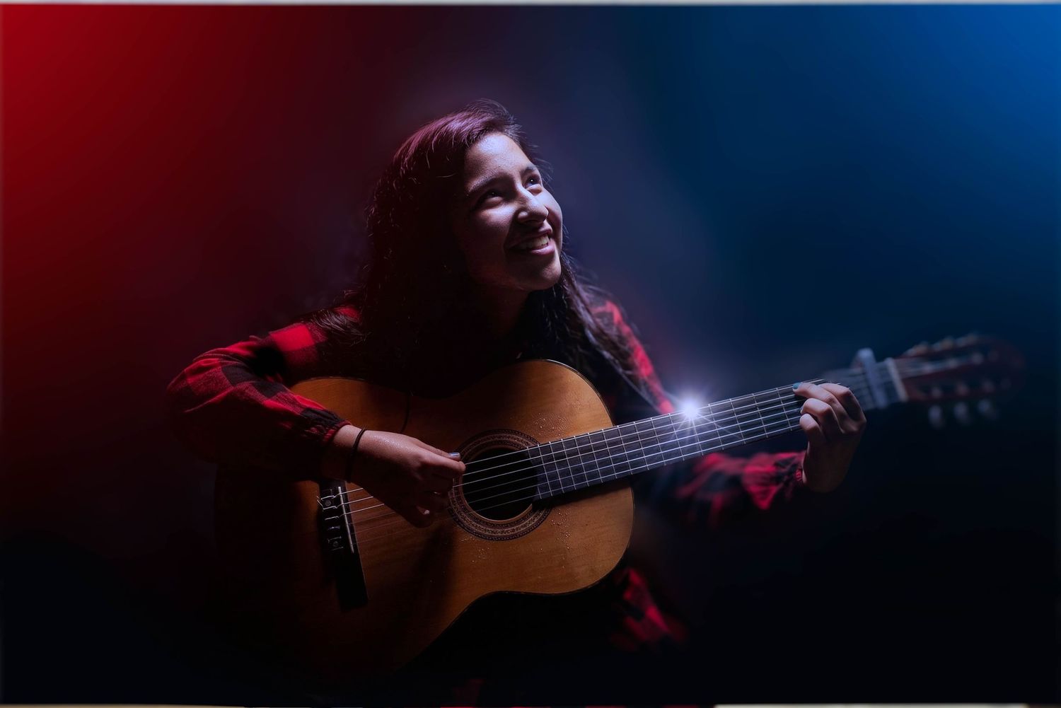 Musician playing guitar during a dramatic studio portrait session.