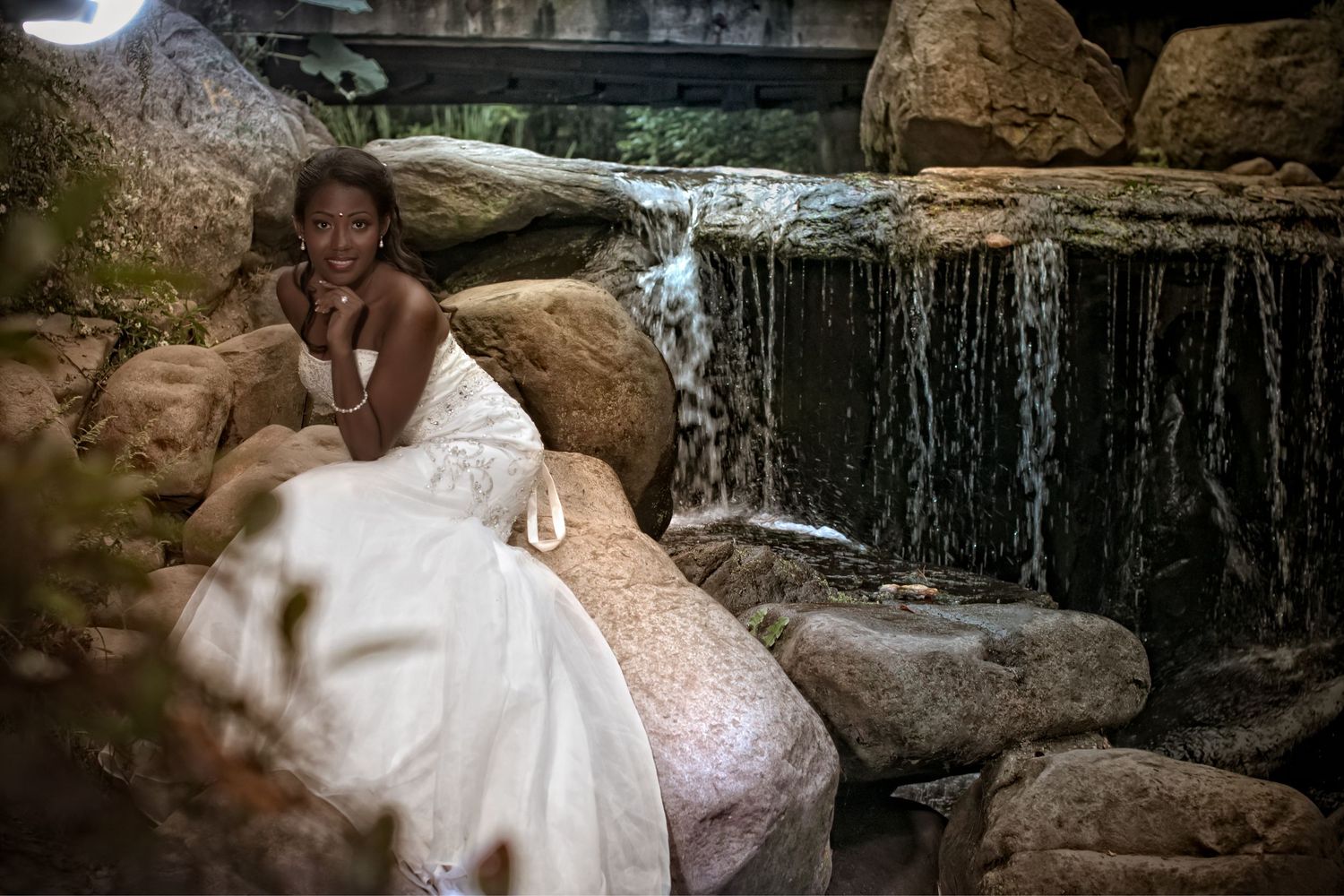 Bride posing near waterfall in romantic outdoor wedding portrait
