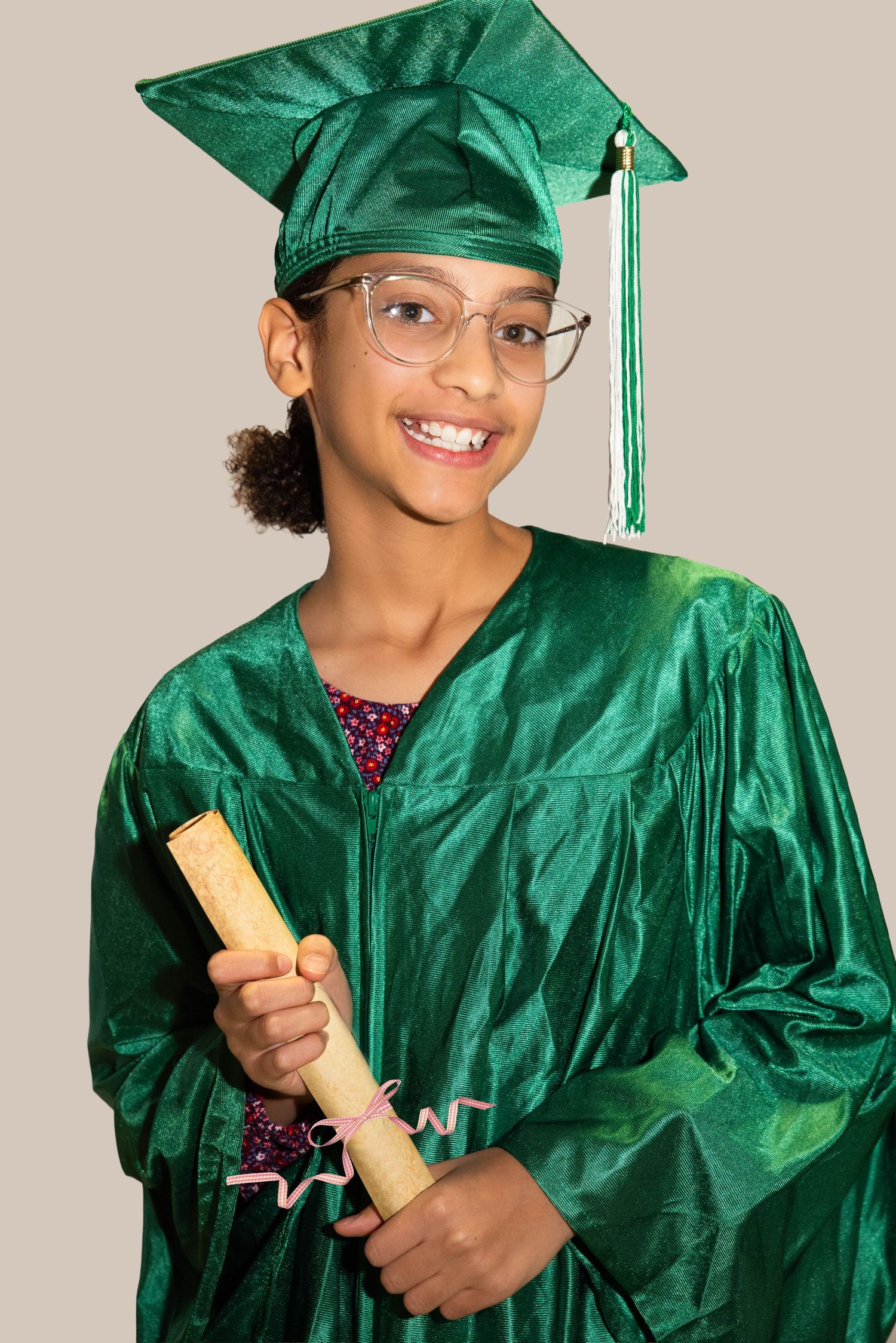 Graduate wearing a green cap and gown holding a diploma for a studio graduation portrait.