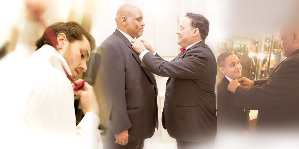 Groom getting ready with assistance adjusting tie before wedding ceremony