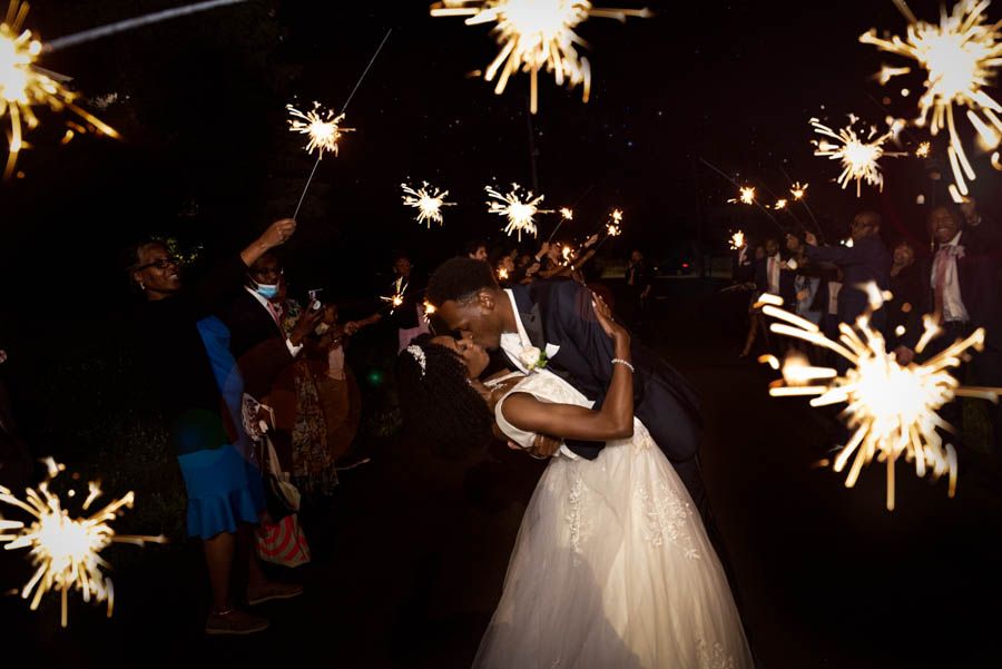 Bride and groom kissing during sparkler exit at night wedding celebration in NYC