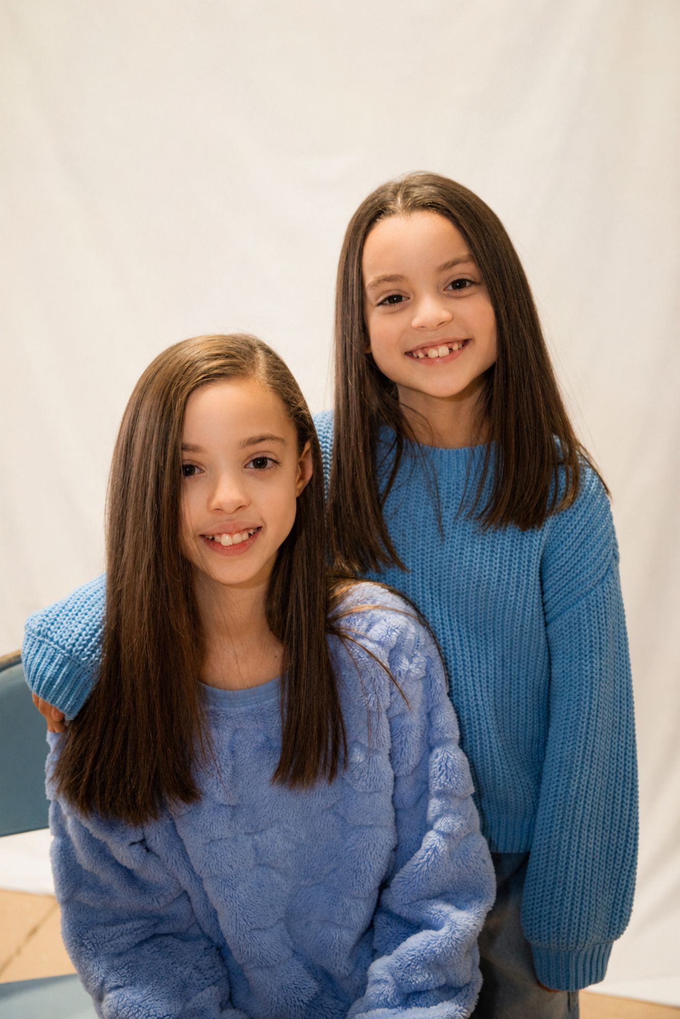 Two children posing together for a studio portrait by Magic All Moment Photography.