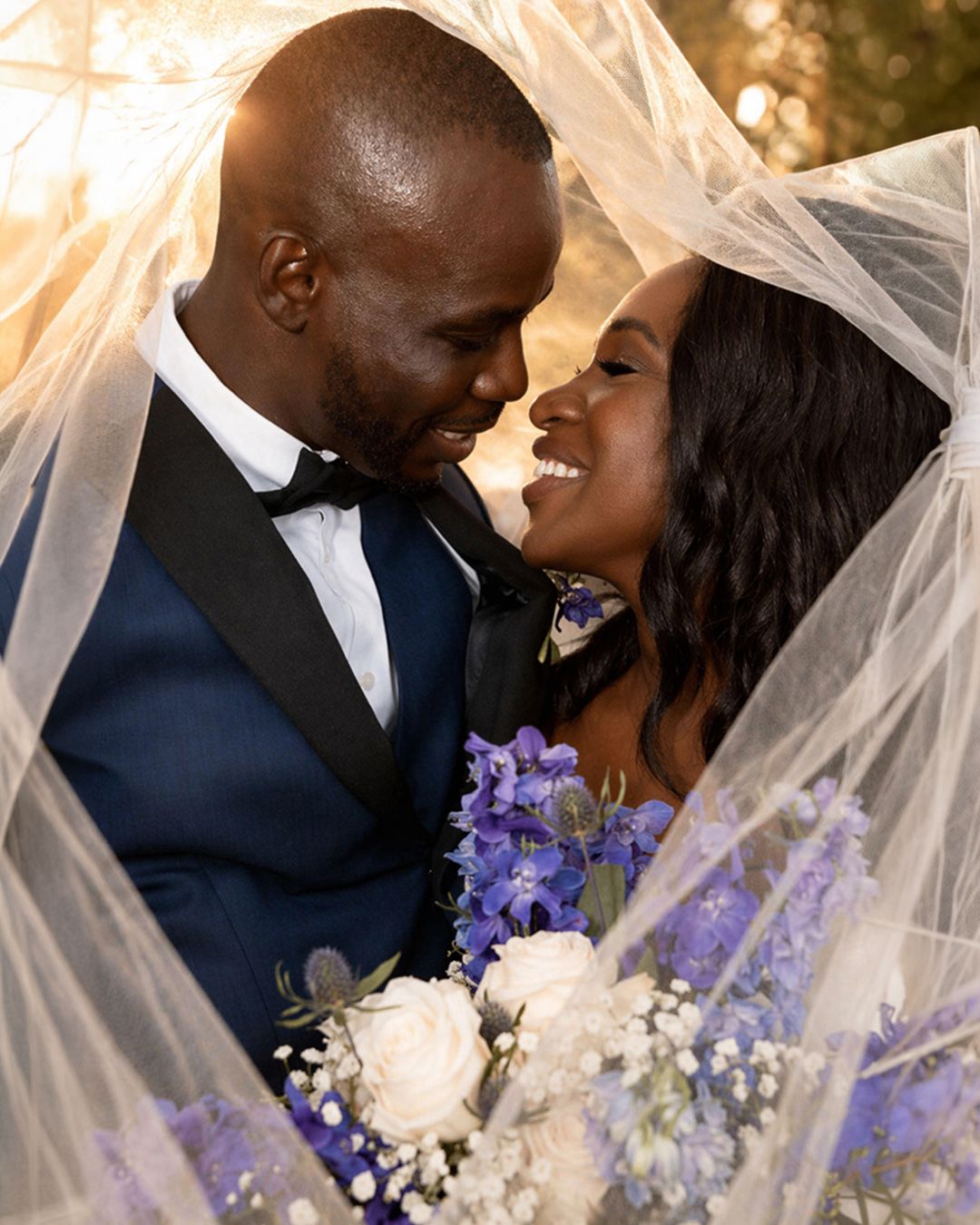 Bride and groom sharing a romantic kiss under the wedding veil during their portrait session. by Magic All Moment Photography.