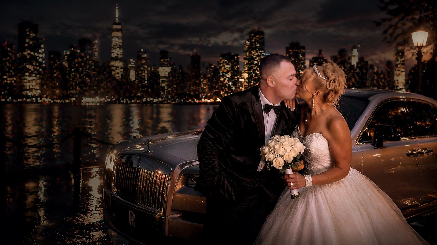 Bride and groom kissing at night with city lights in background