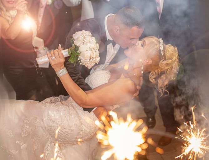 Bride and groom sharing a dip kiss surrounded by sparklers during a wedding celebration in NYC