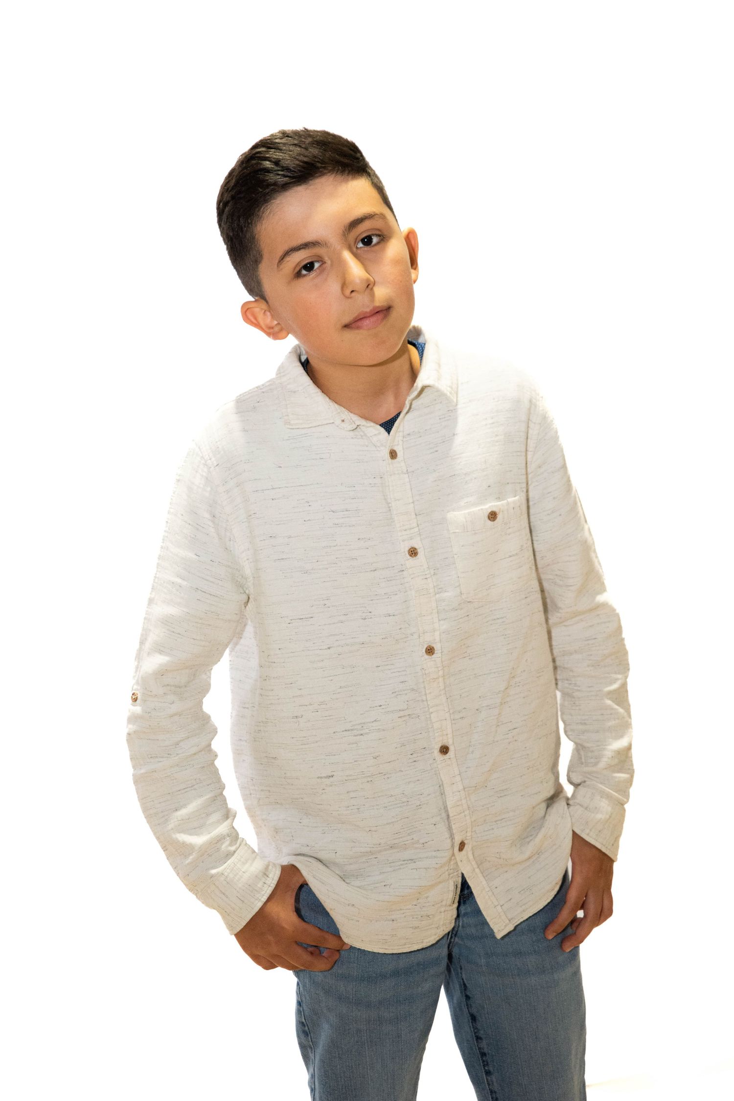 Child posing in a white shirt for a simple studio portrait.