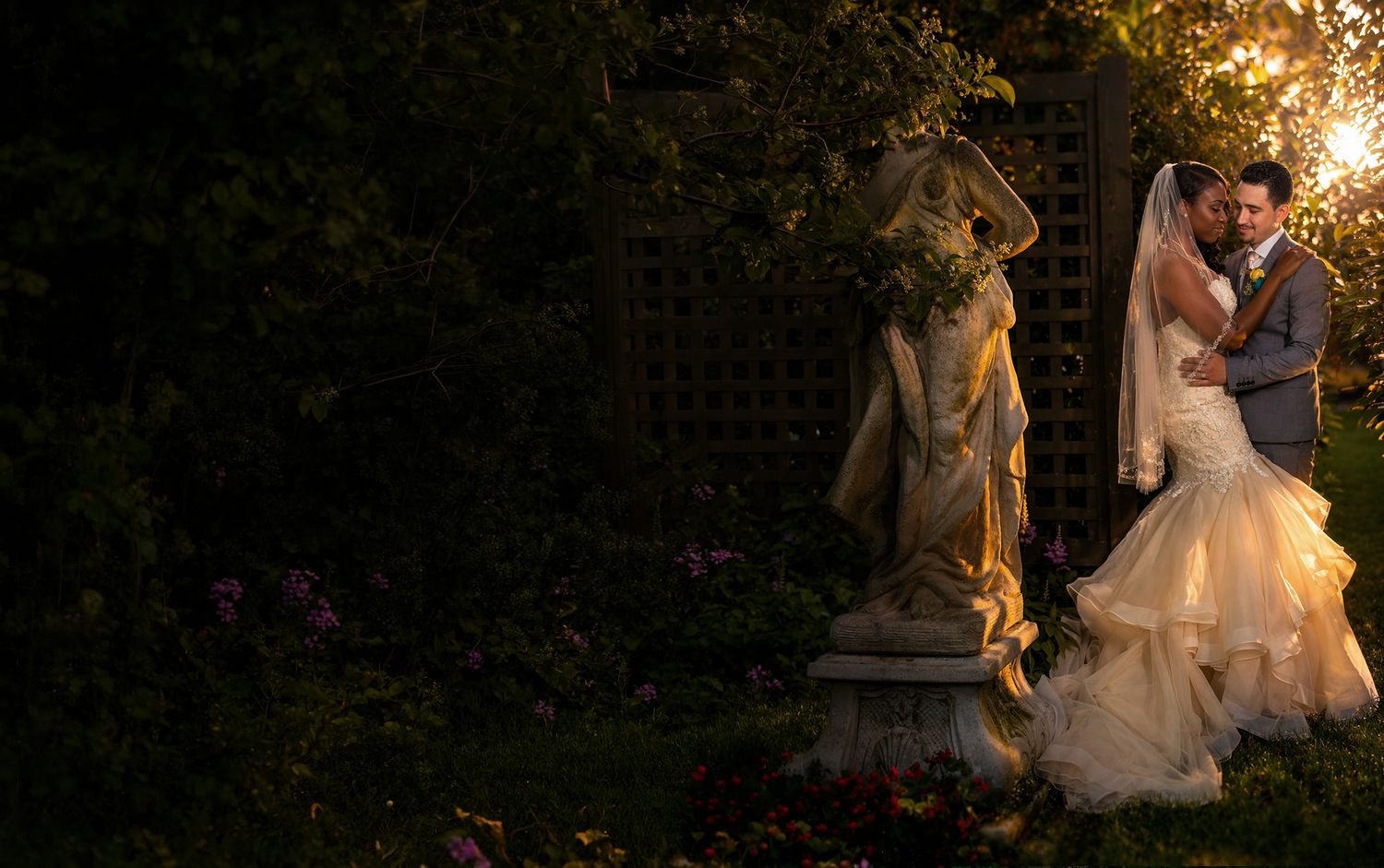 Bride and groom standing together in garden during sunset
