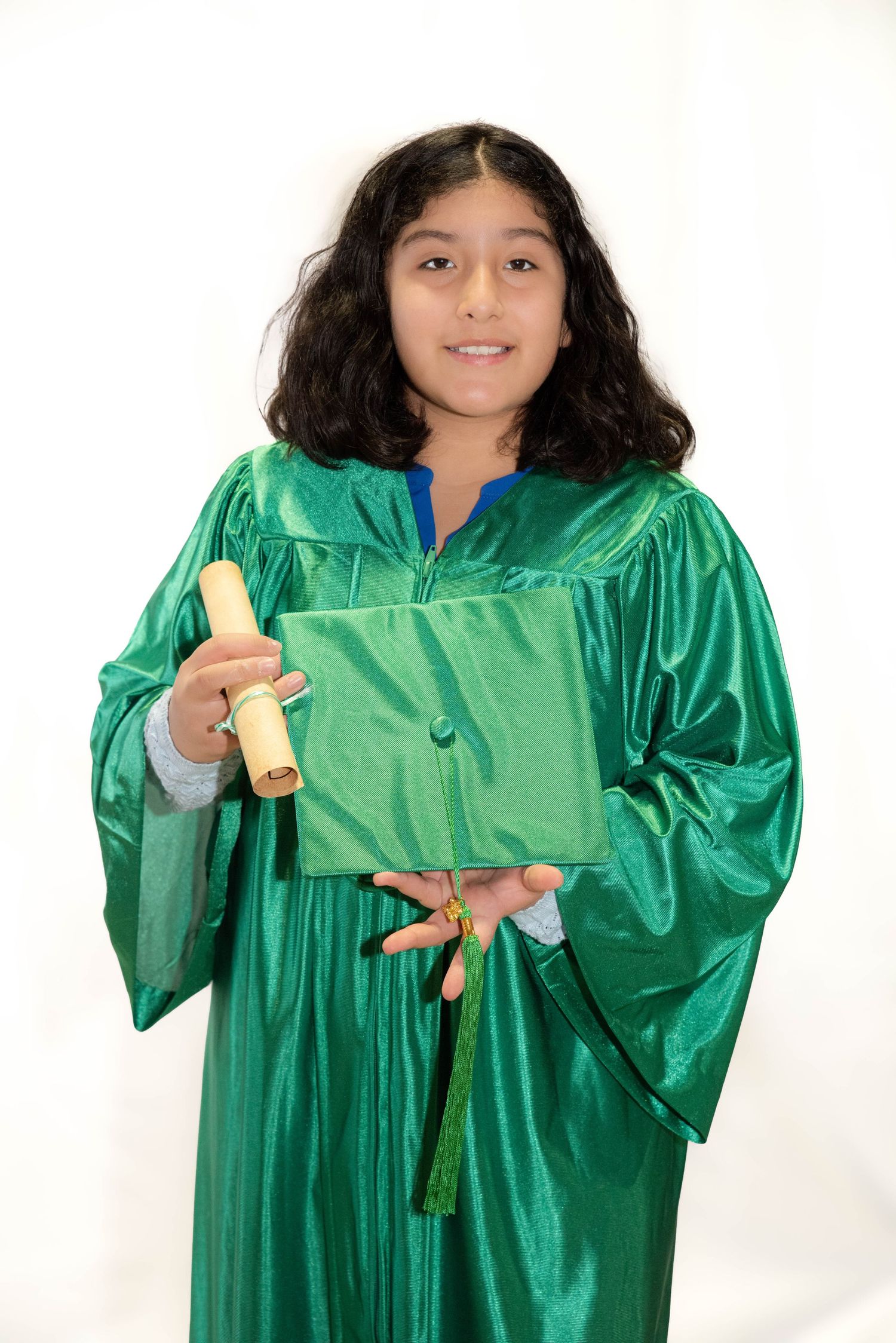 Graduate wearing a green cap and gown holding a diploma for a studio graduation portrait.