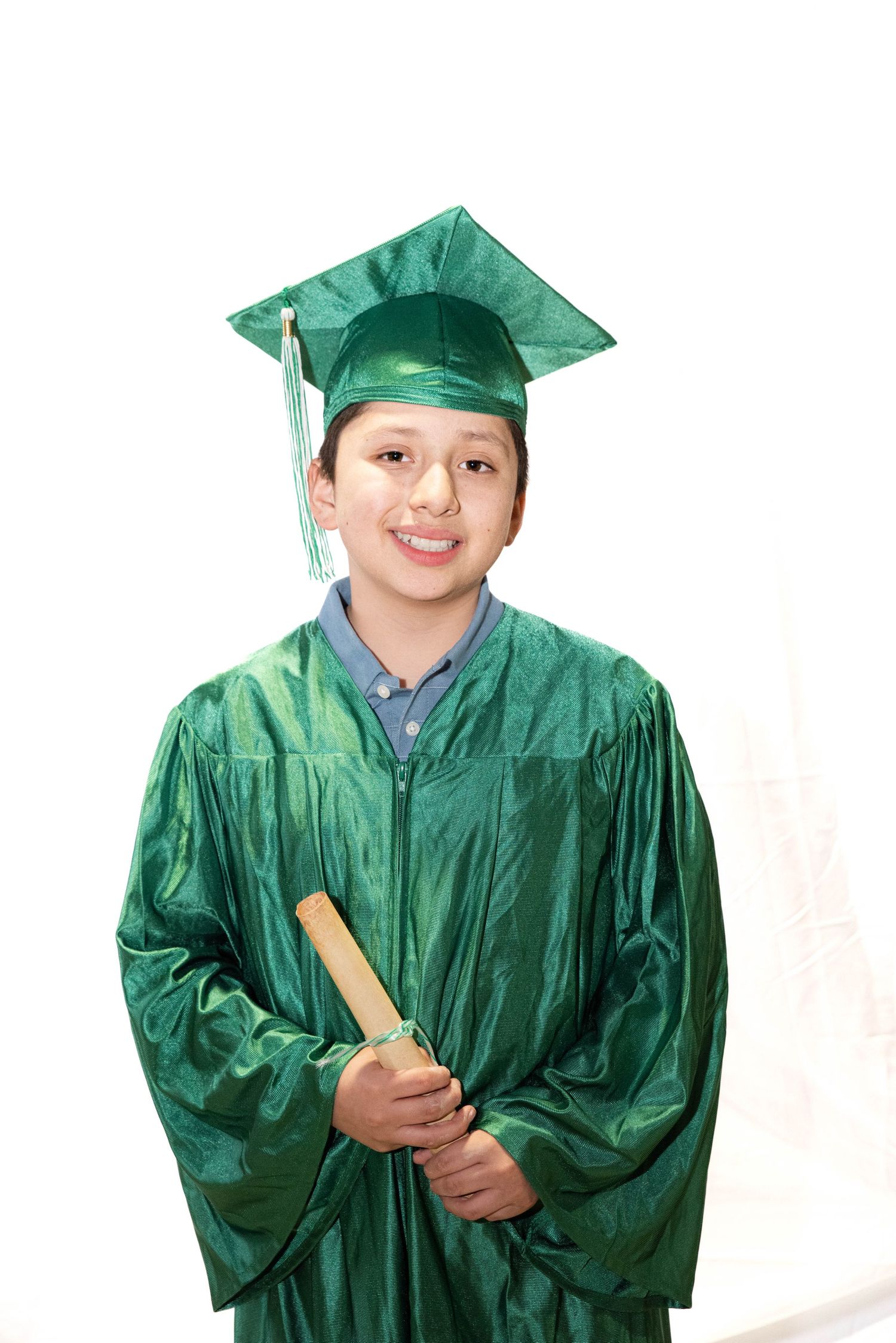 Child wearing a green graduation cap and gown for a studio graduation portrait.