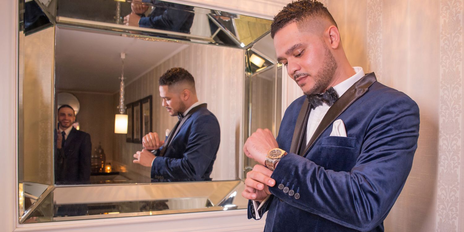 Groom adjusting cufflinks in mirror during wedding preparation