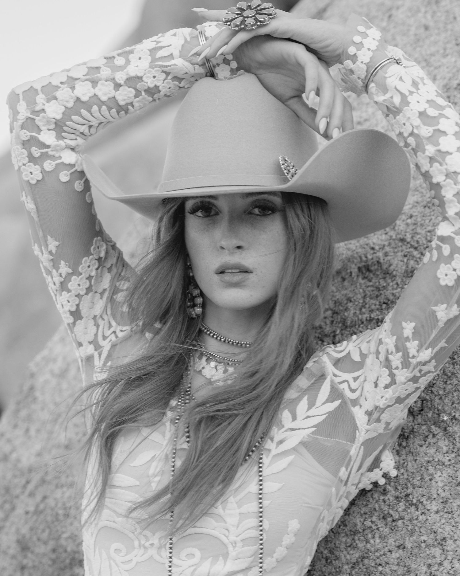 Black and white close-up of bride in lace dress and cowboy hat with turquoise earrings and jewelry.