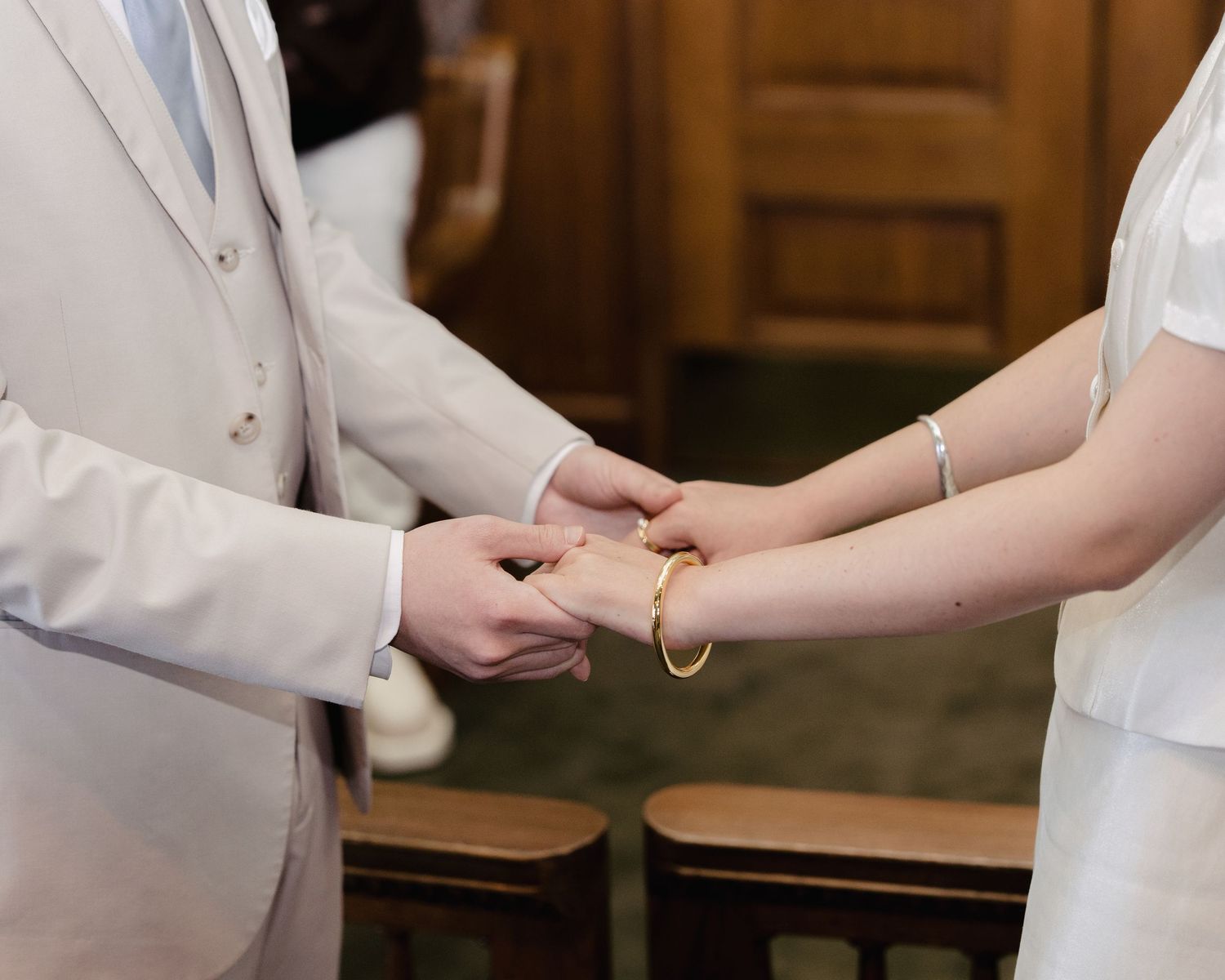 Bride and groom exchange rings during an intimate courthouse wedding ceremony while holding hands.