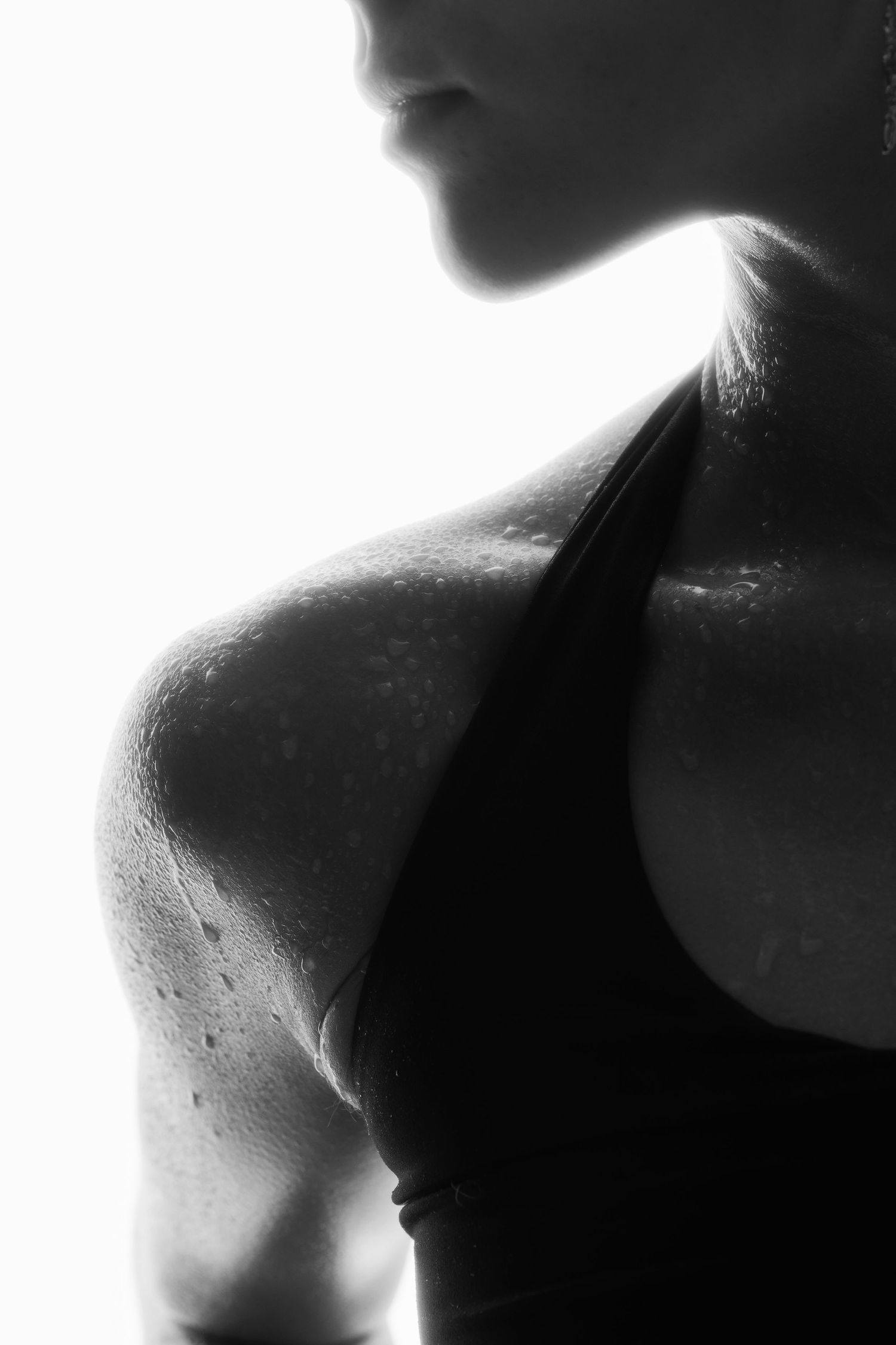 Dramatic black and white close-up of a sweaty athletic woman's shoulder.