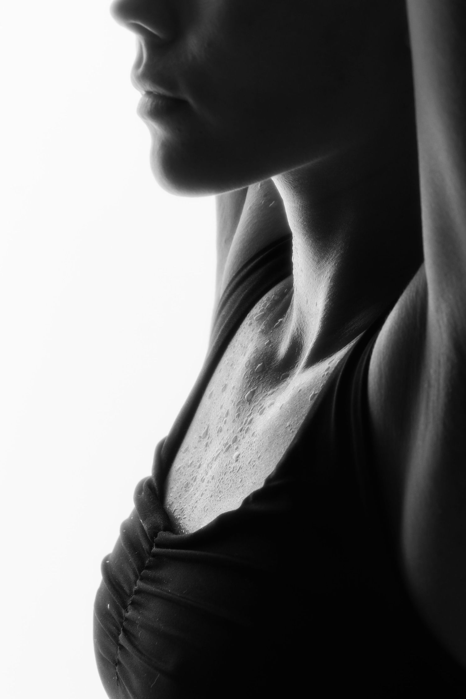 Black and white profile of a woman with sweat on her chest in a tank top.