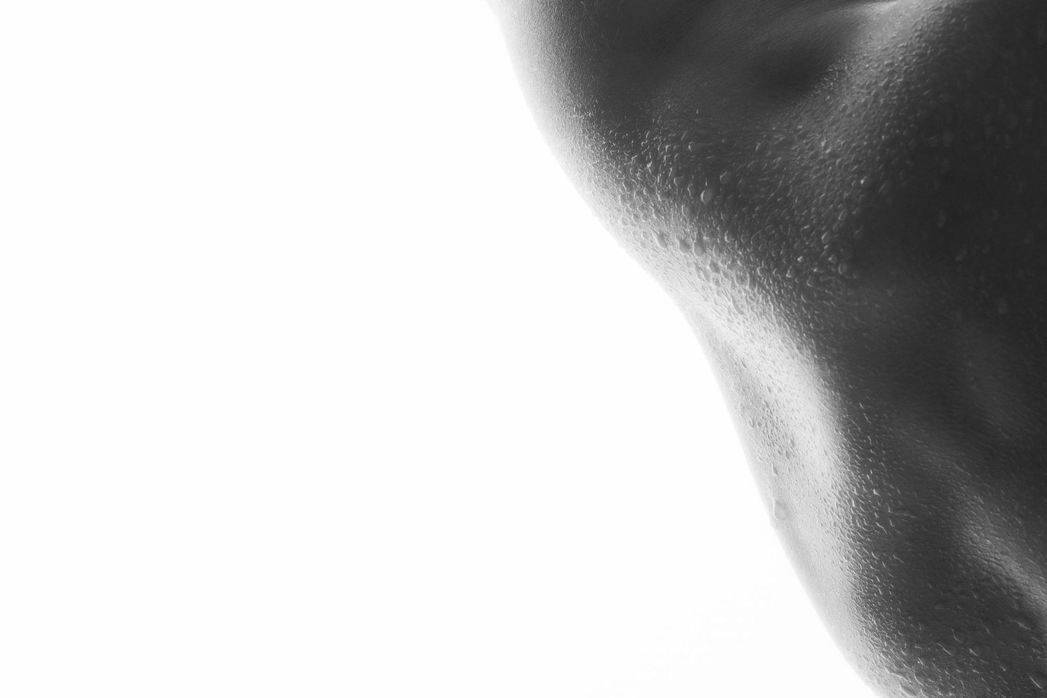 Black and white close-up of wet human skin with water droplets, artistic body photography.