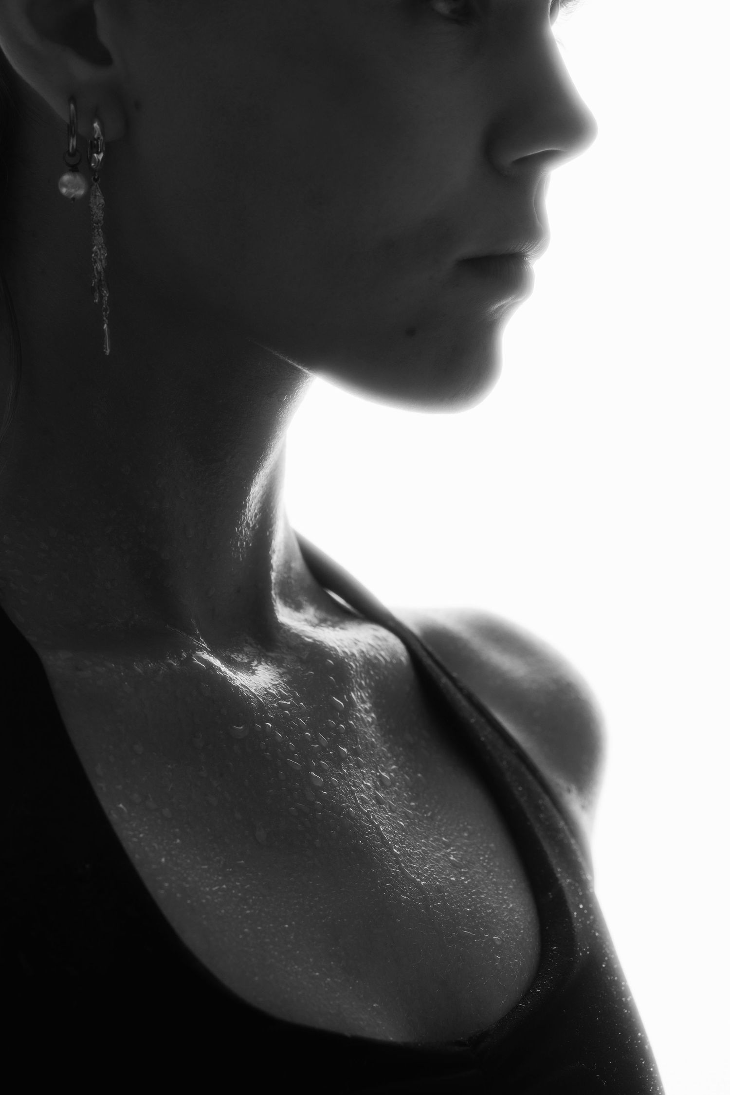 Black and white side profile of a fit woman with sweat on her collarbone.