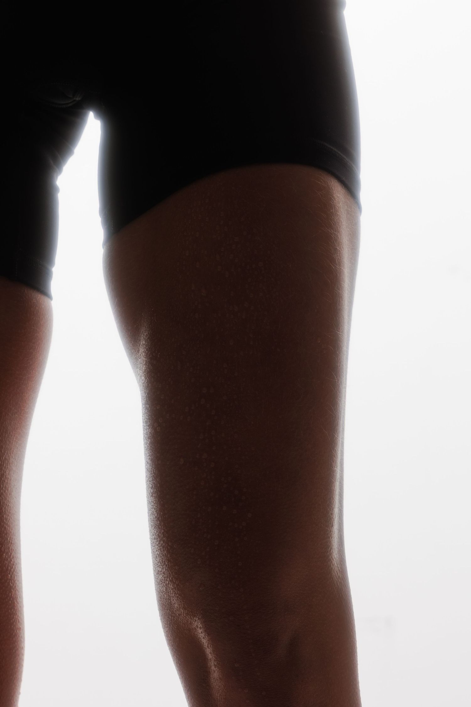 Close-up of sweat droplets on an athletic woman's thigh in black shorts.