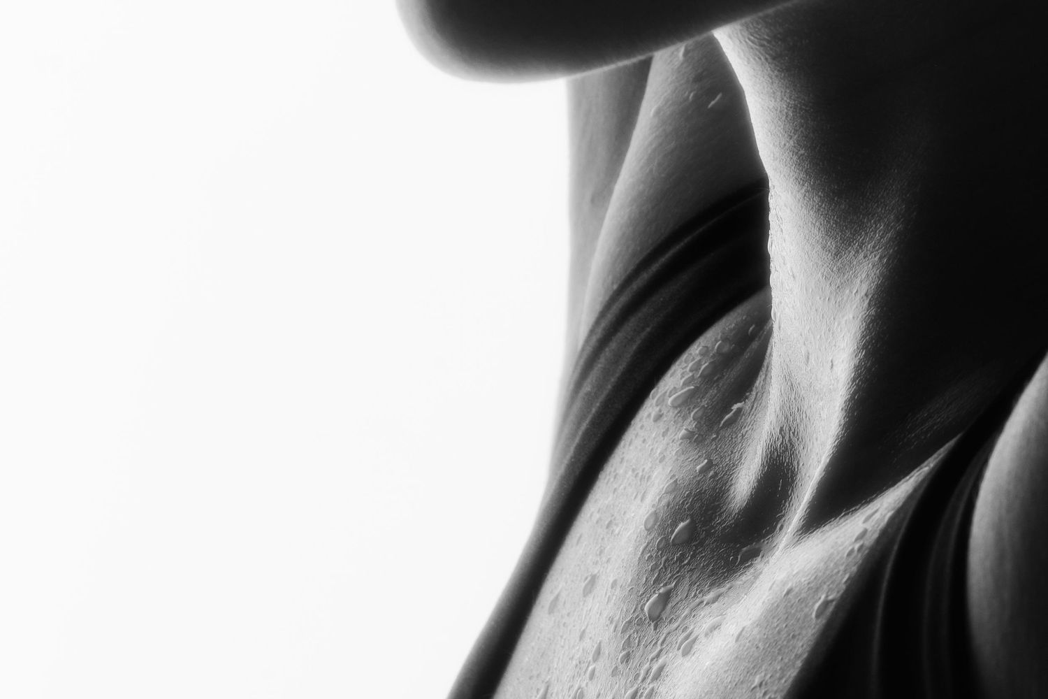 Monochrome close-up of sweat droplets on a woman's neck and chest area.
