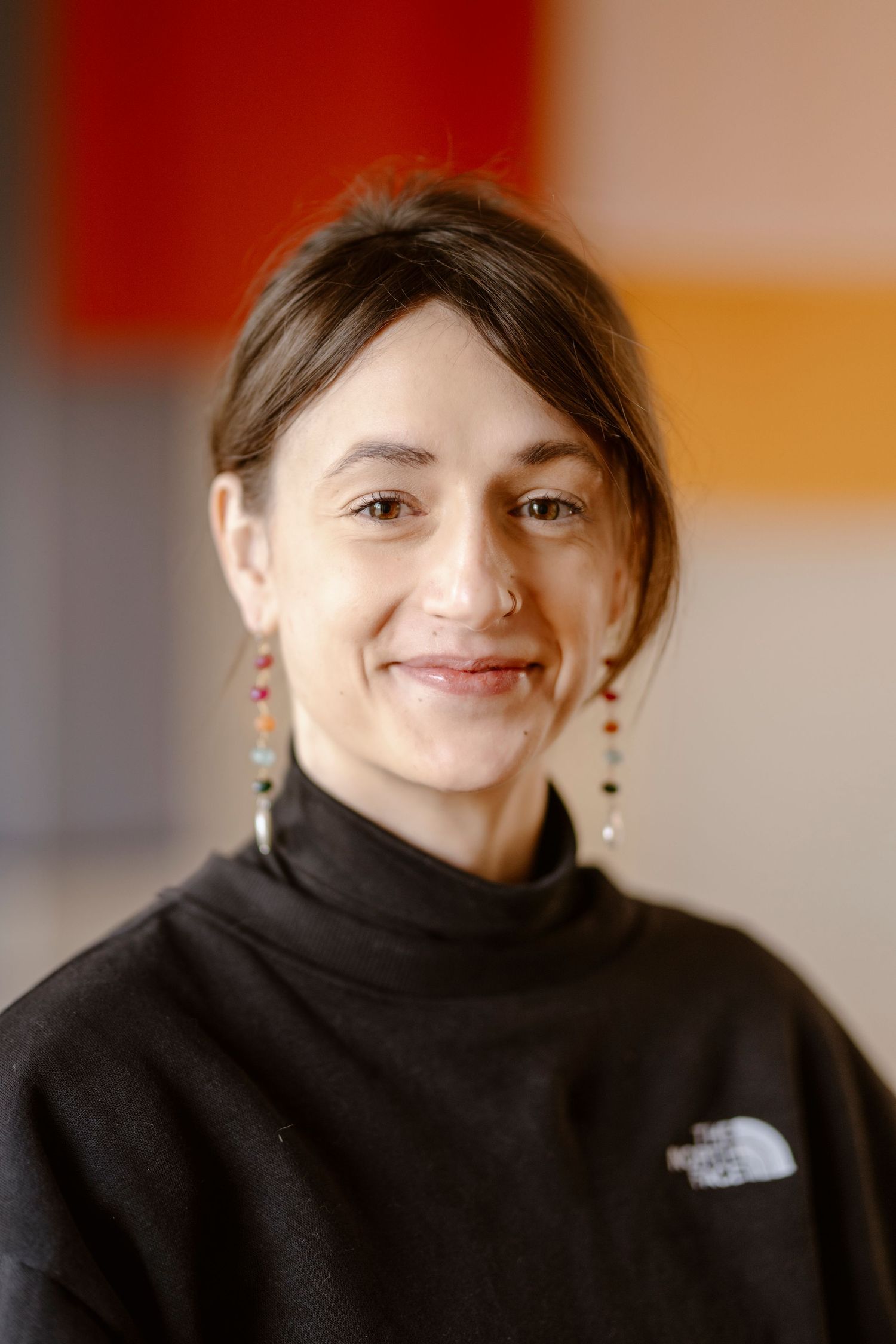 Close-up portrait of someone wearing a black turtleneck and dangling earrings.