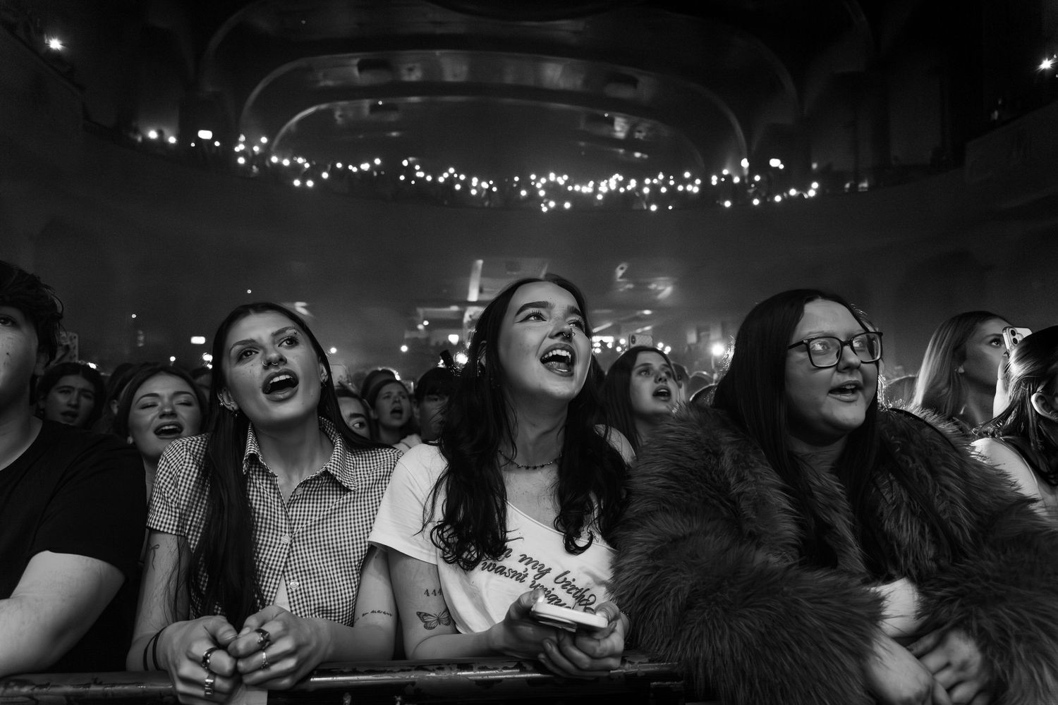 A busy concert crowd in o2 academy Glasgow holding their phones up lighting the room during an emotional song in black and white.