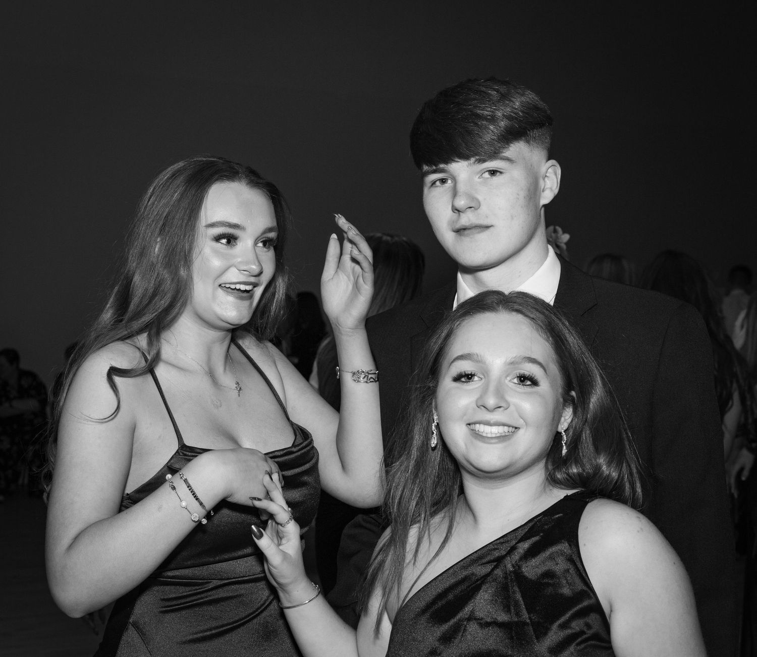 Group of friends posing for the camera at a winter ball party event in the hall of a school in Edinburgh in black and white.