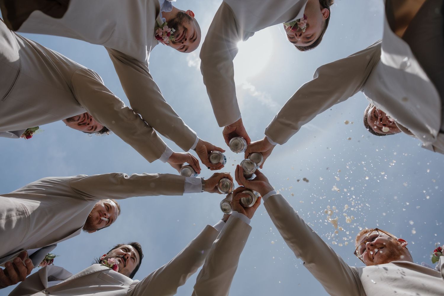 A group of people stand in a circle formation viewed from below against a bright sky background.