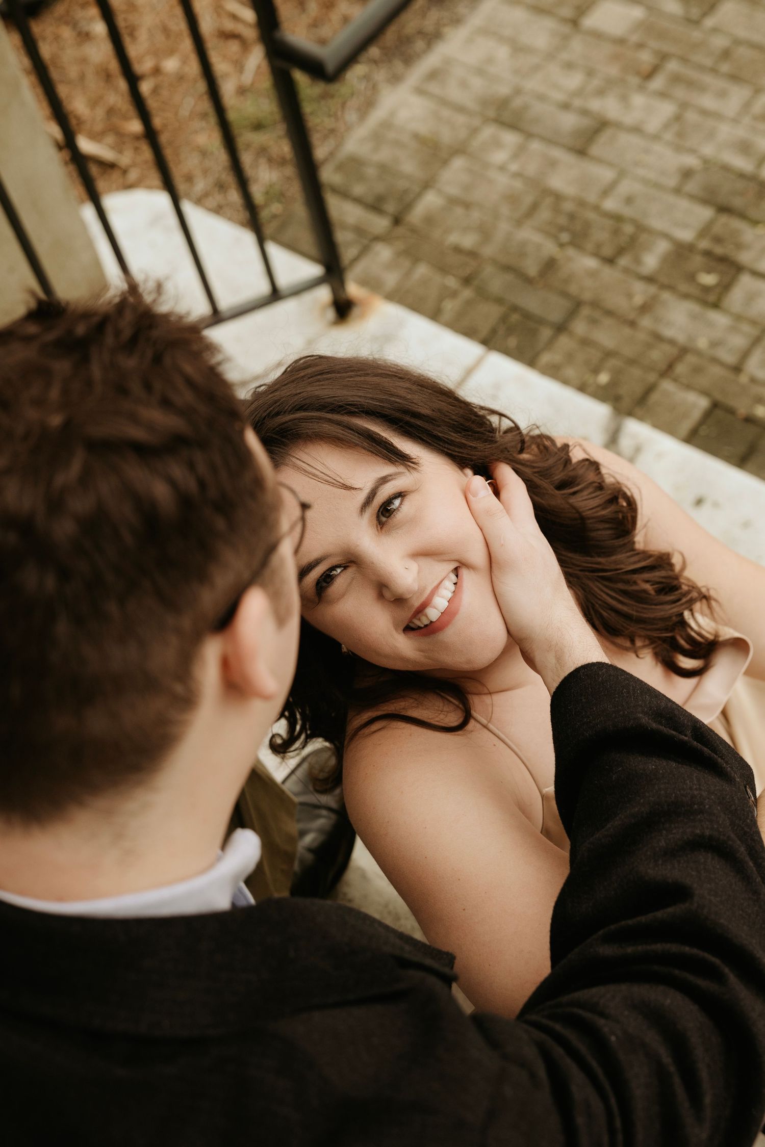 Intimate engagement moment captured on stone steps with soft natural lighting.