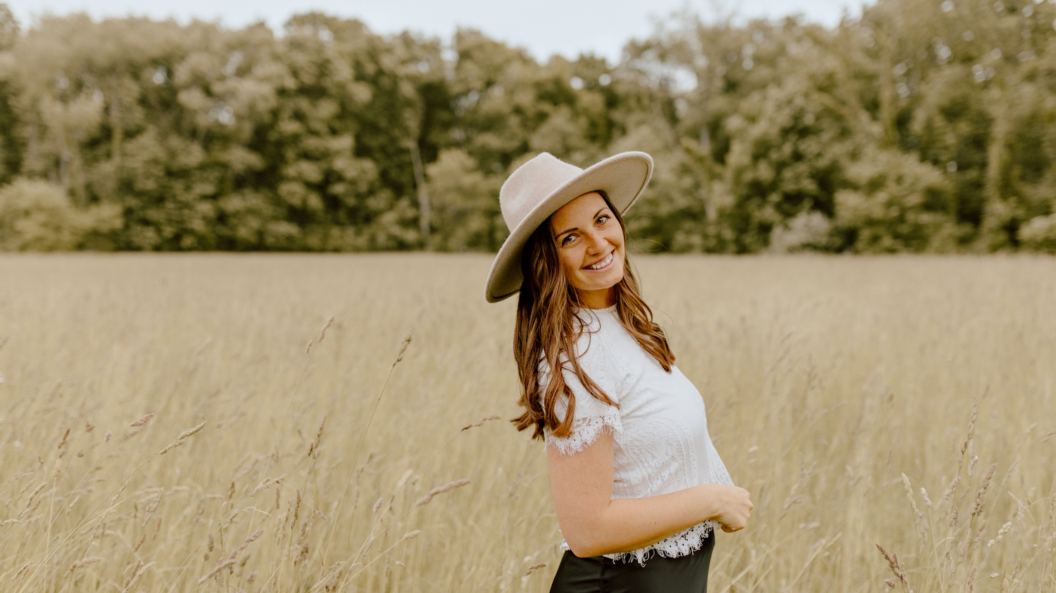 Sarah, wife, in golden hayfield smiling.