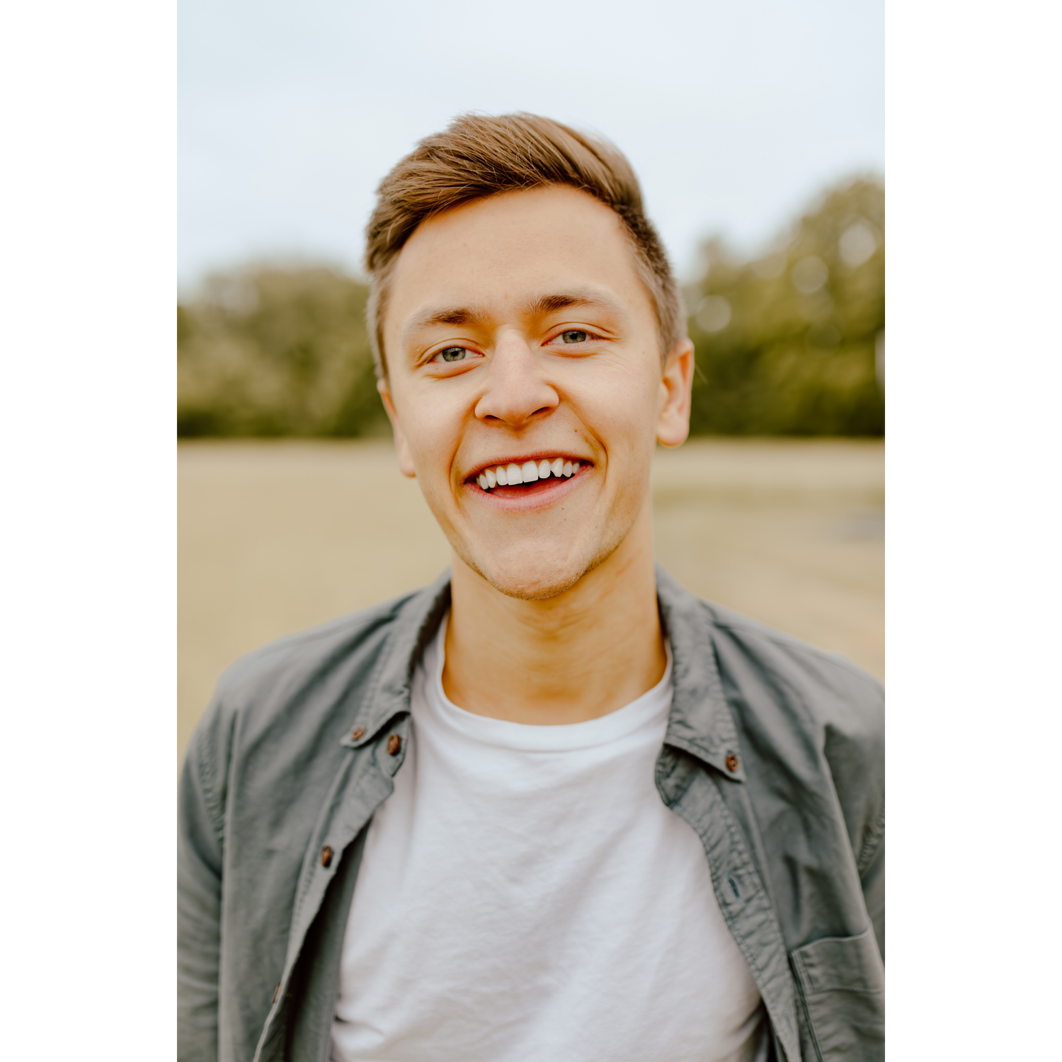 Husband, Jonathan, smiling for a close up headshot in field.