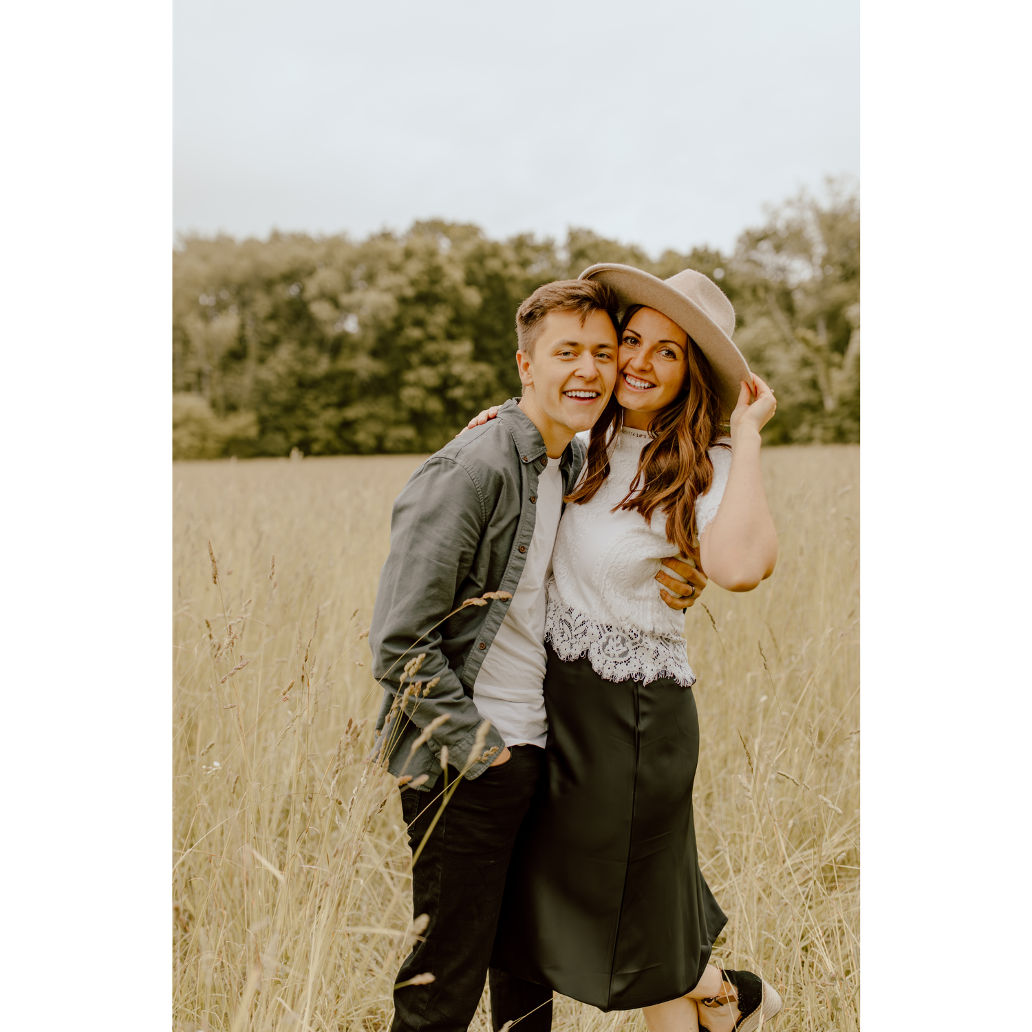 Owners of photography business in a golden hayfield hugging and smiling.