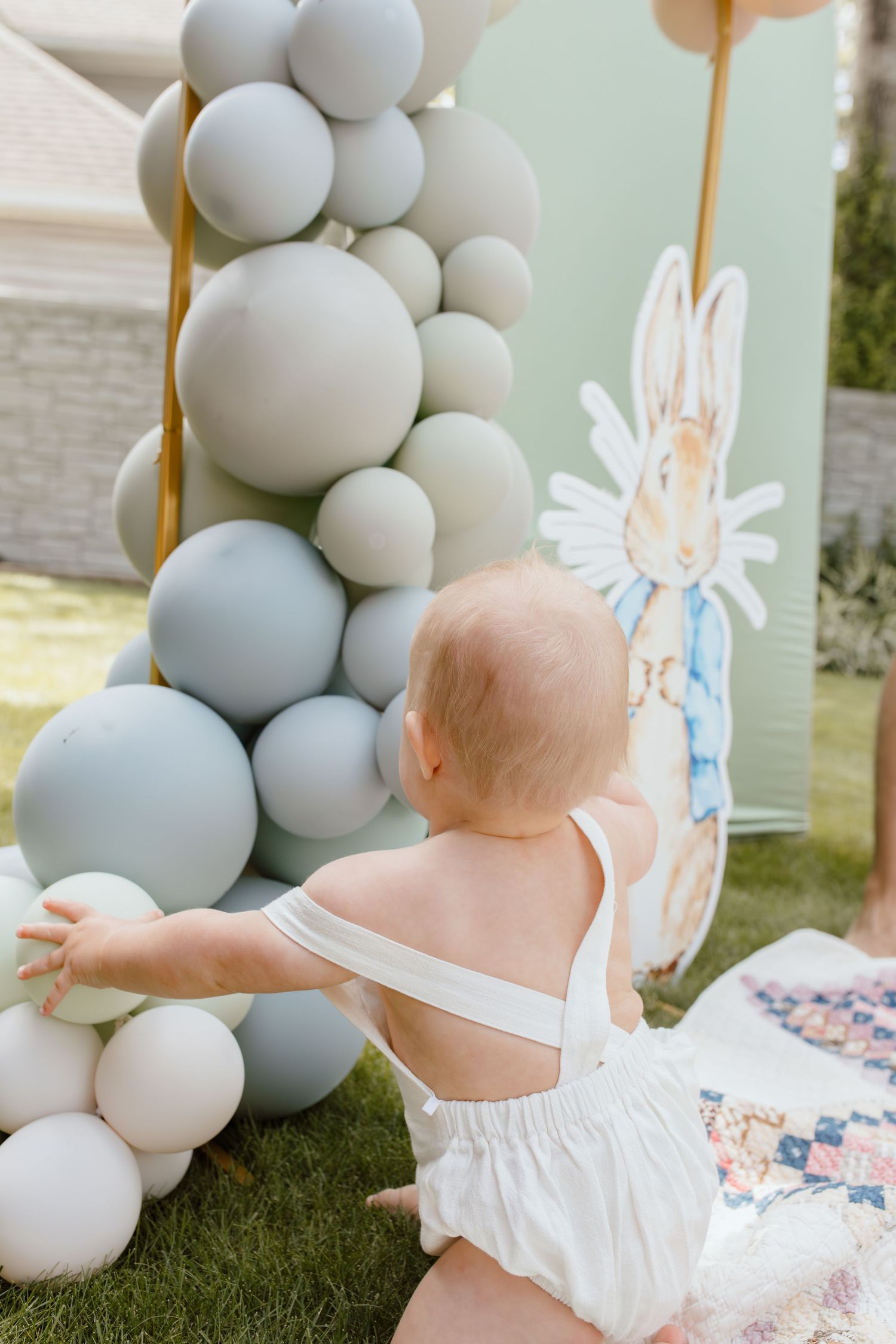One year old grabbing pastel balloons at a Peter rabbit themed birthday party.