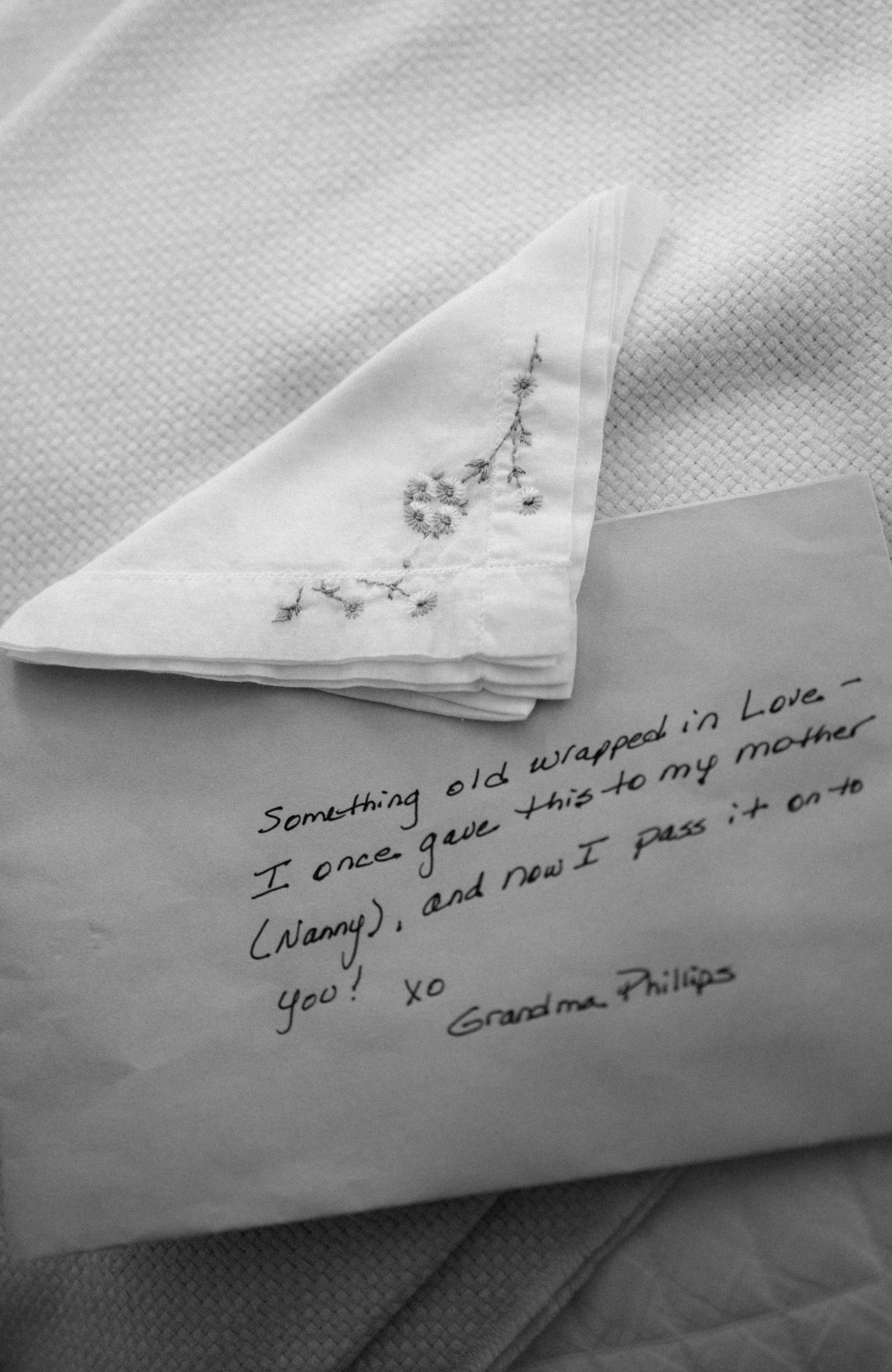 Black and white photo of an embroidered handkerchief with a handwritten note from Grandma Phillips passing it on with love.