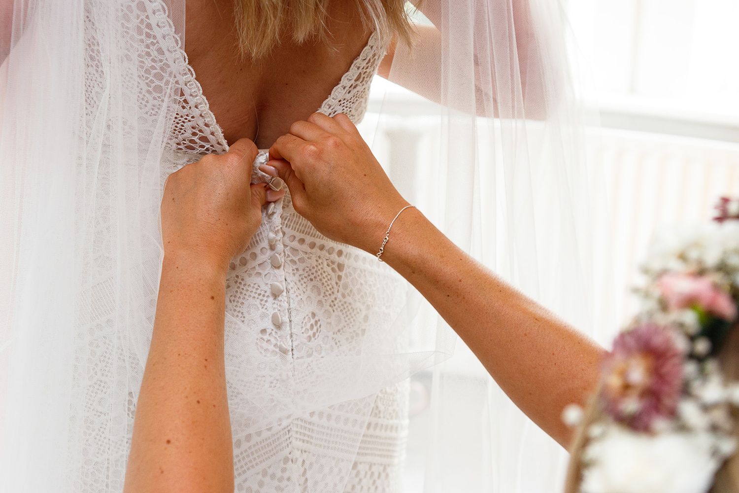 A bride adjusts her delicate lace veil while getting ready for her wedding ceremony.