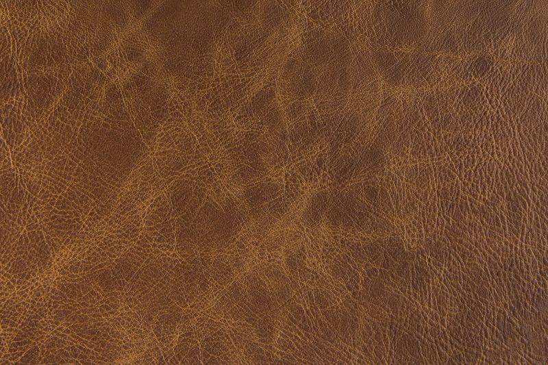 Close-up texture of rich brown leather with natural grain patterns and variations in tone.