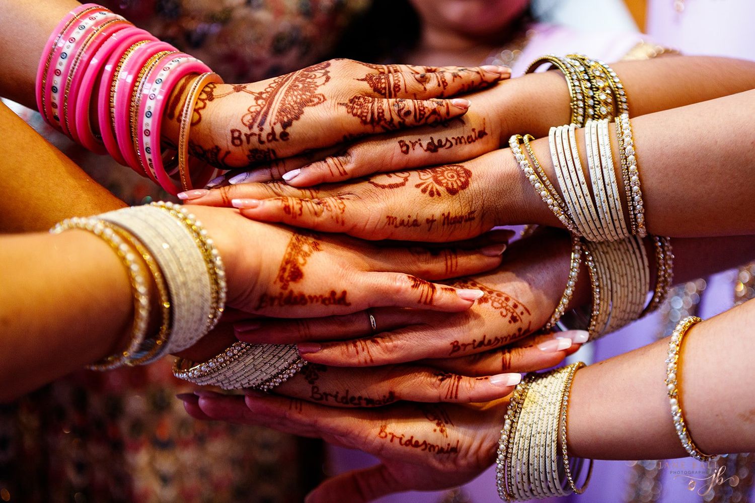 Hands adorned with traditional henna designs and colorful bangles come together in a festive Indian celebration.